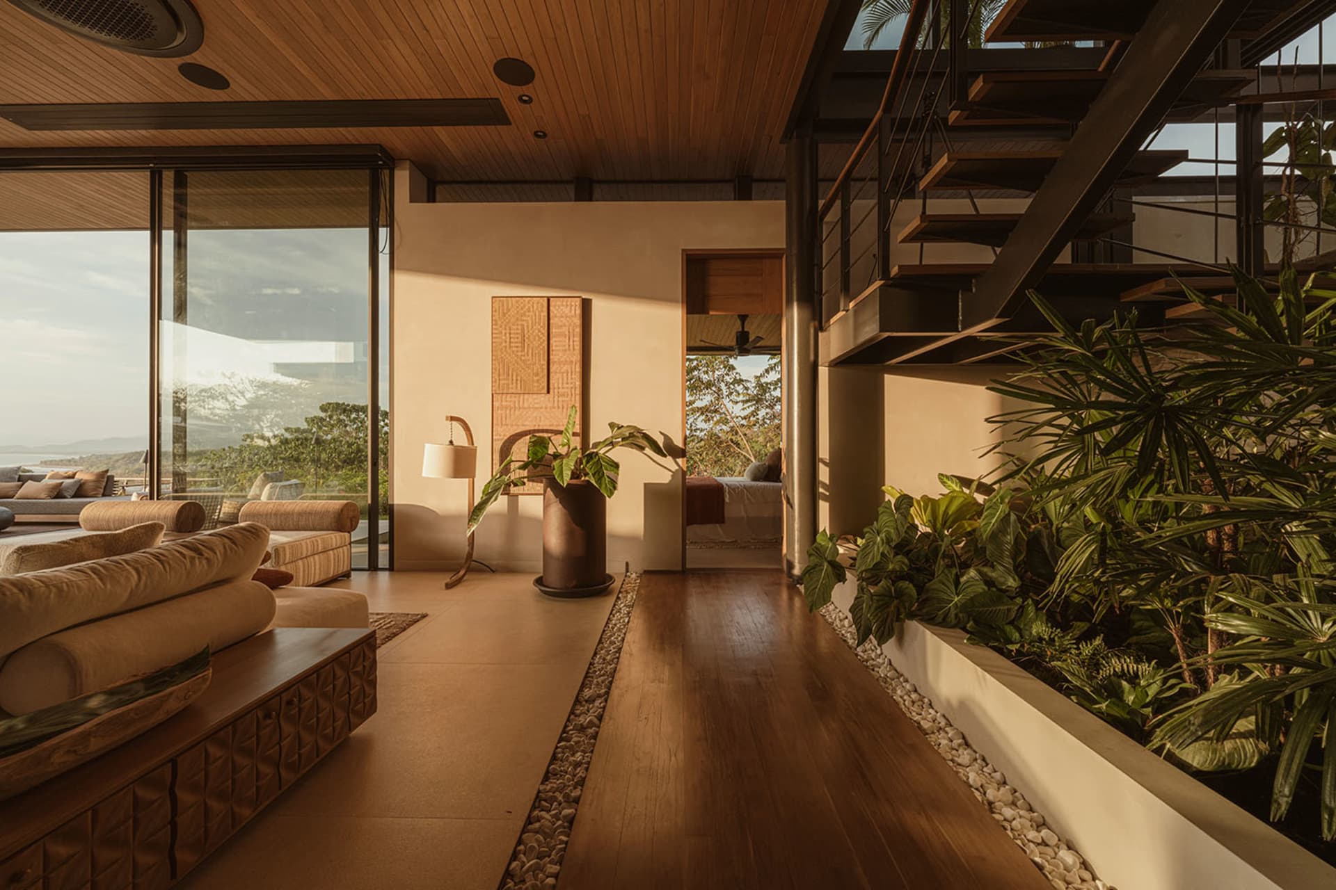 Modern living room with concrete floor, glass walls, and wooden furniture.