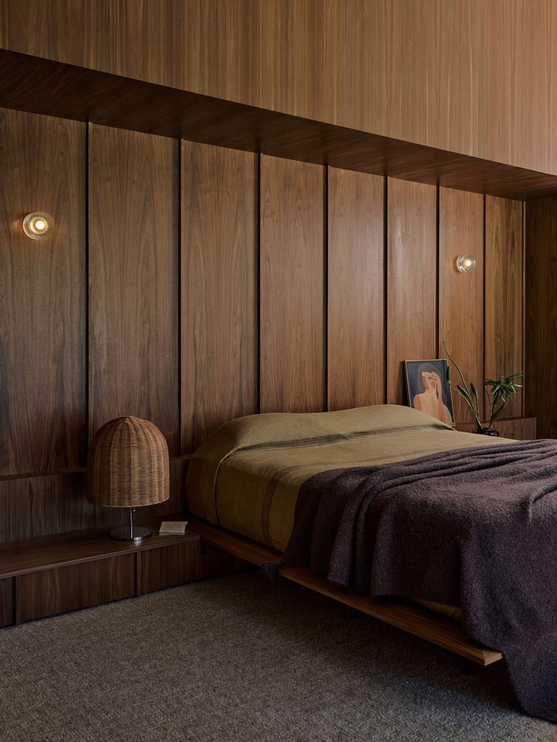 A modern minimalist bedroom featuring wooden paneling, a bed with a wooden platform, and soft lighting.