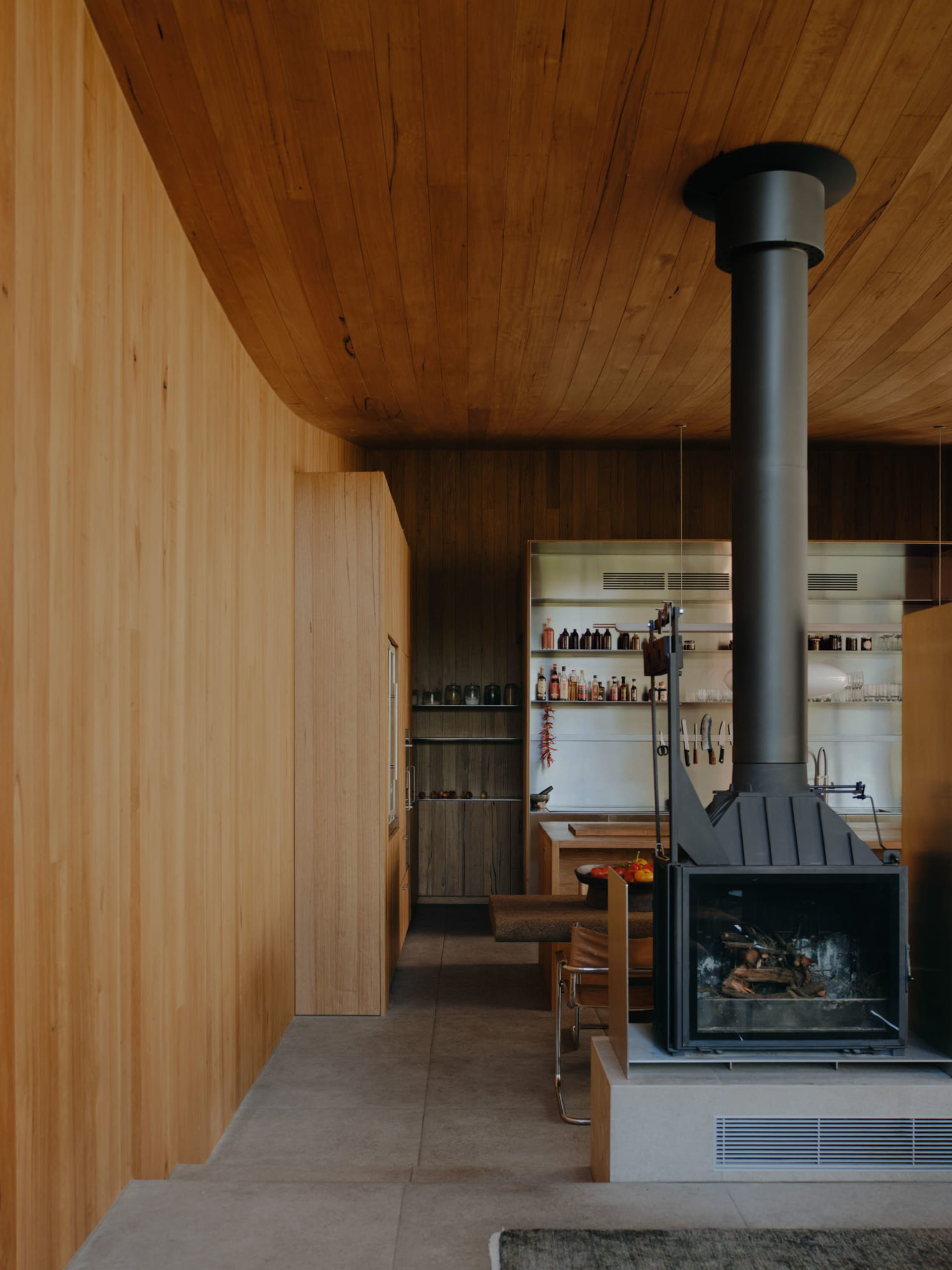 An industrial-style kitchen features wooden walls and a fireplace, creating a cozy and rustic atmosphere.