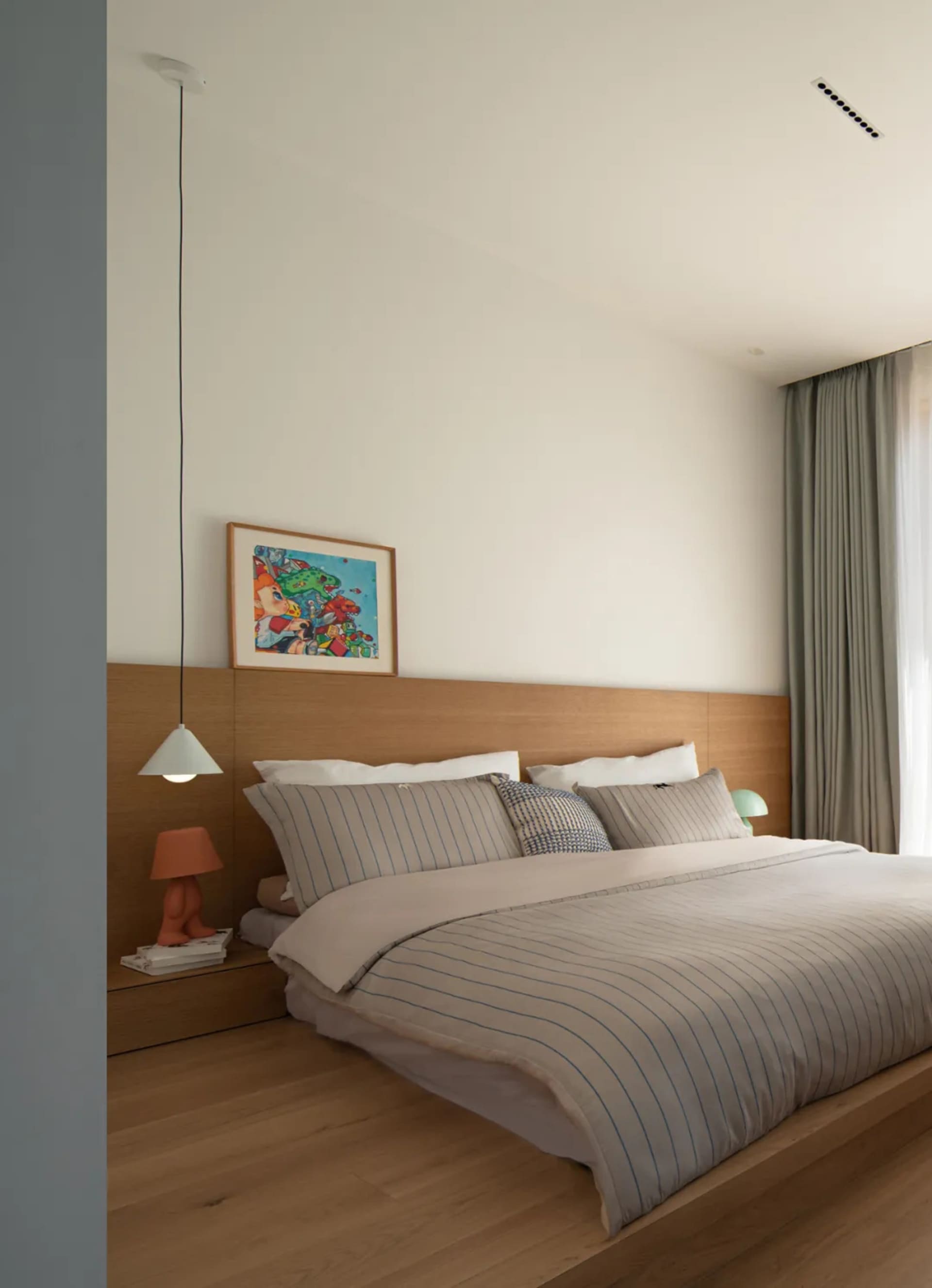 Modern bedroom featuring a wooden platform bed with white bedding and a colorful abstract painting above the headboard.