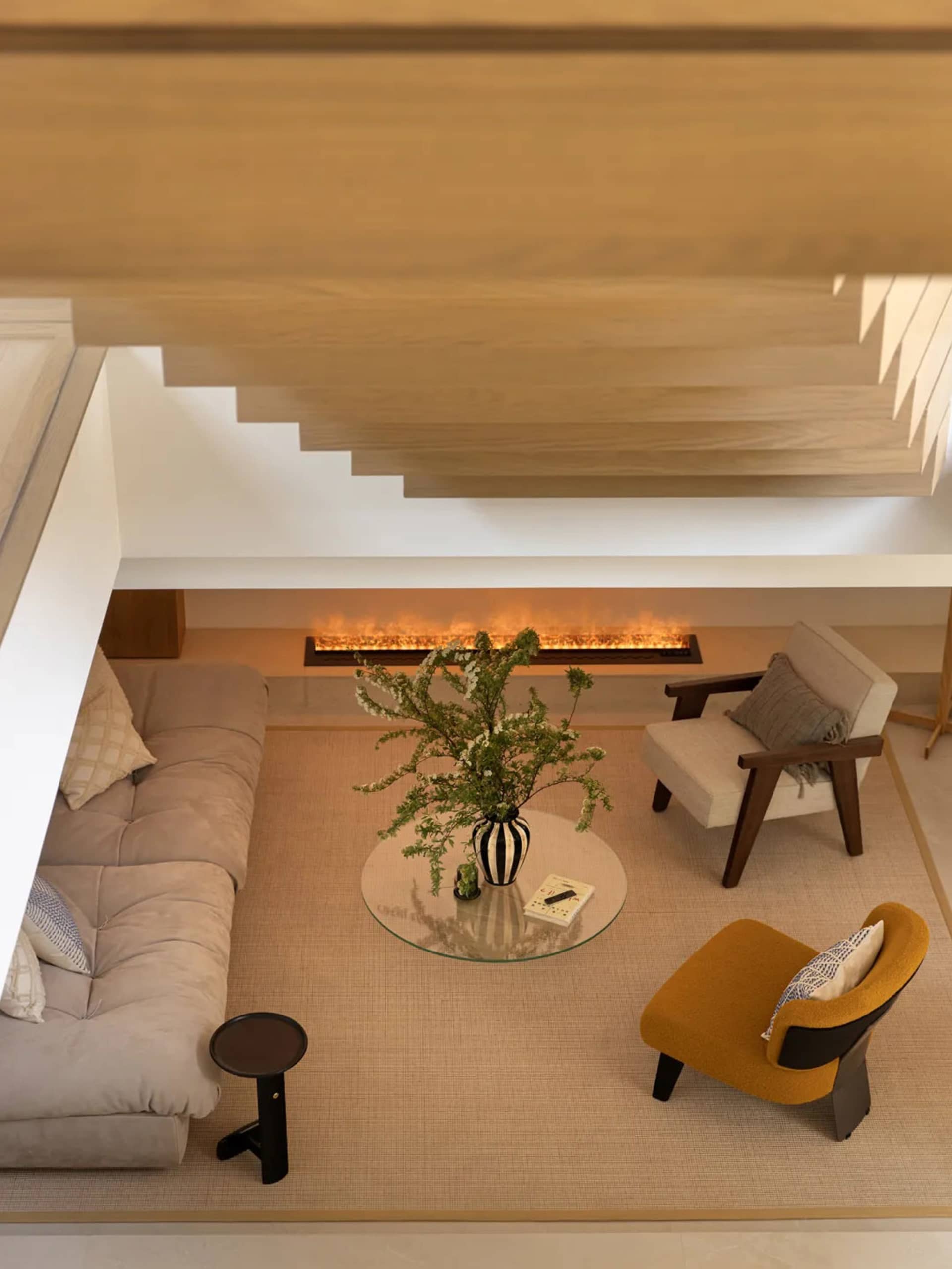 A modern living room with a fireplace, comfortable seating, and a central round coffee table with a vase and natural elements