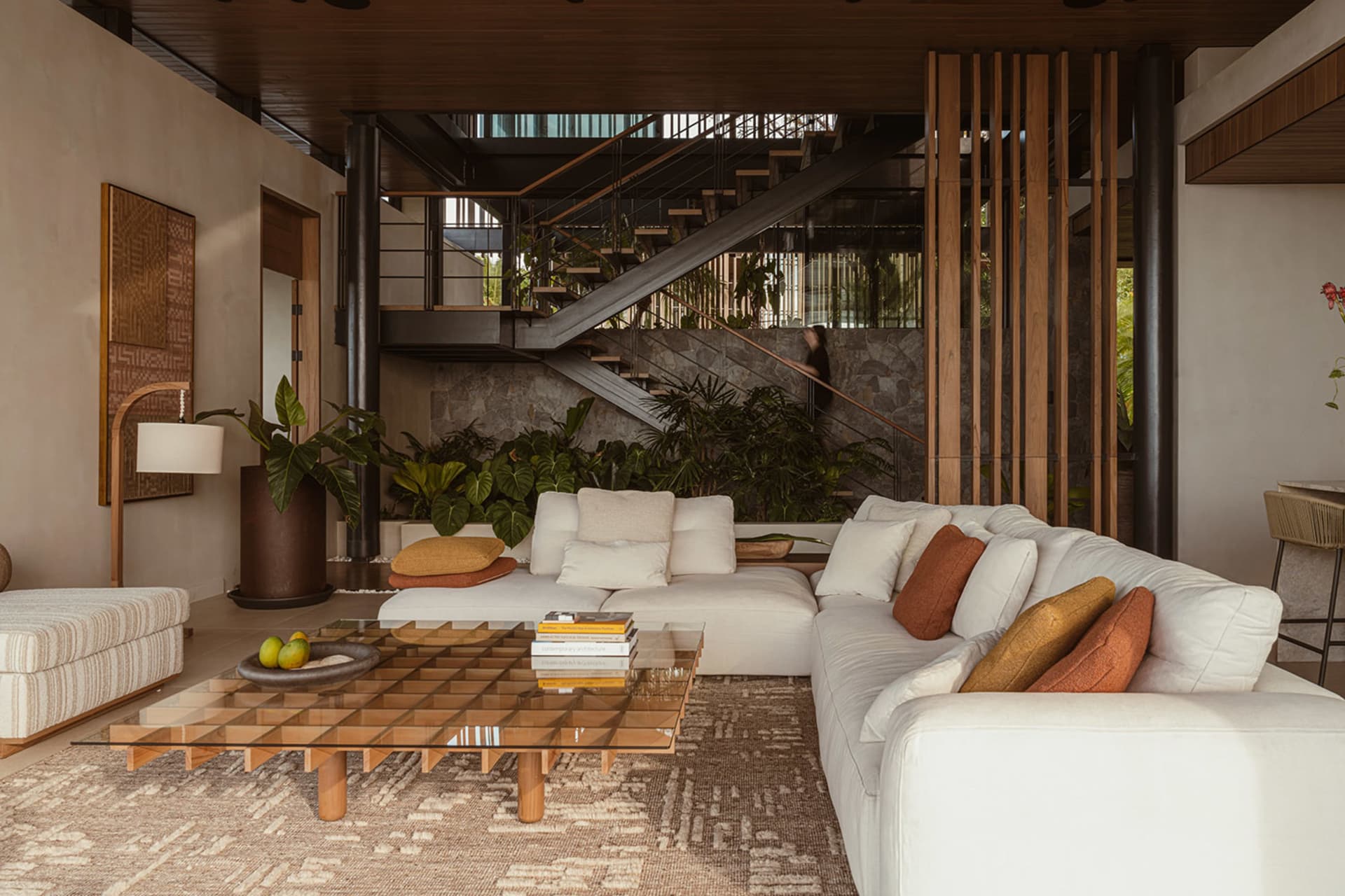 A modern living room with neutral-toned furniture and decor, featuring a cozy sectional, a glass coffee table, and various in