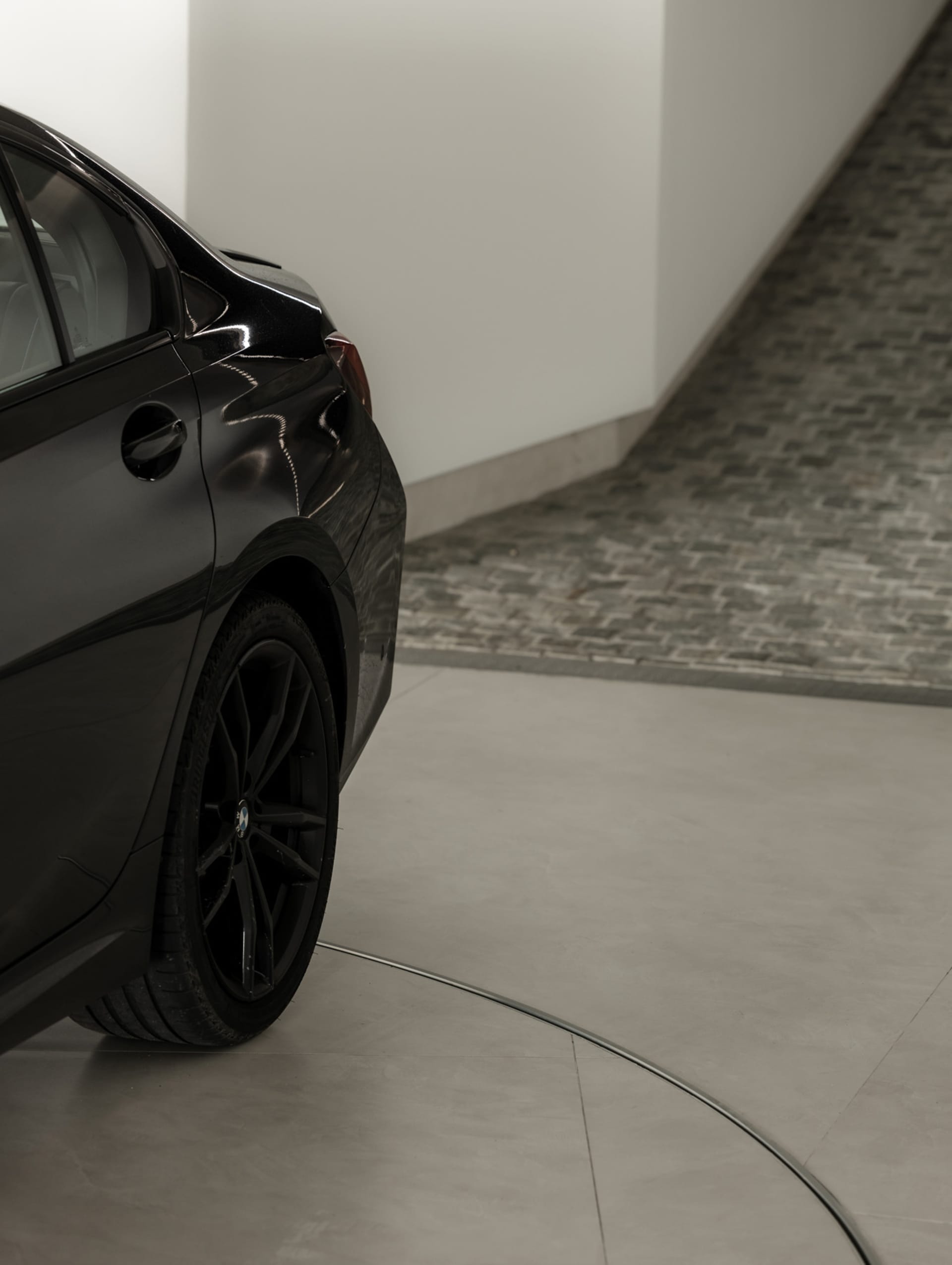 A modern black car parked in a concrete interior