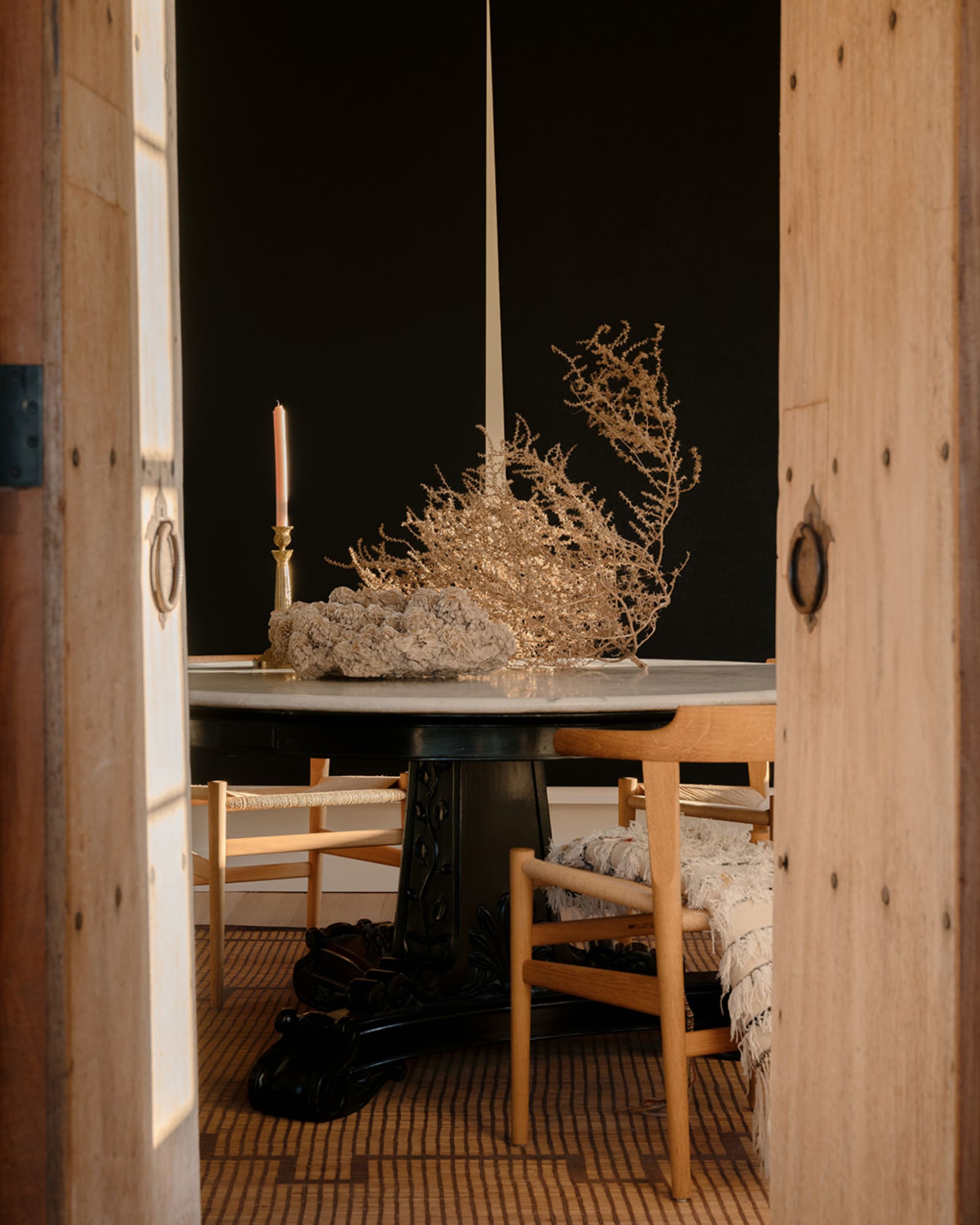 A modern dining room with a wooden table, ceramic vase, and chairs