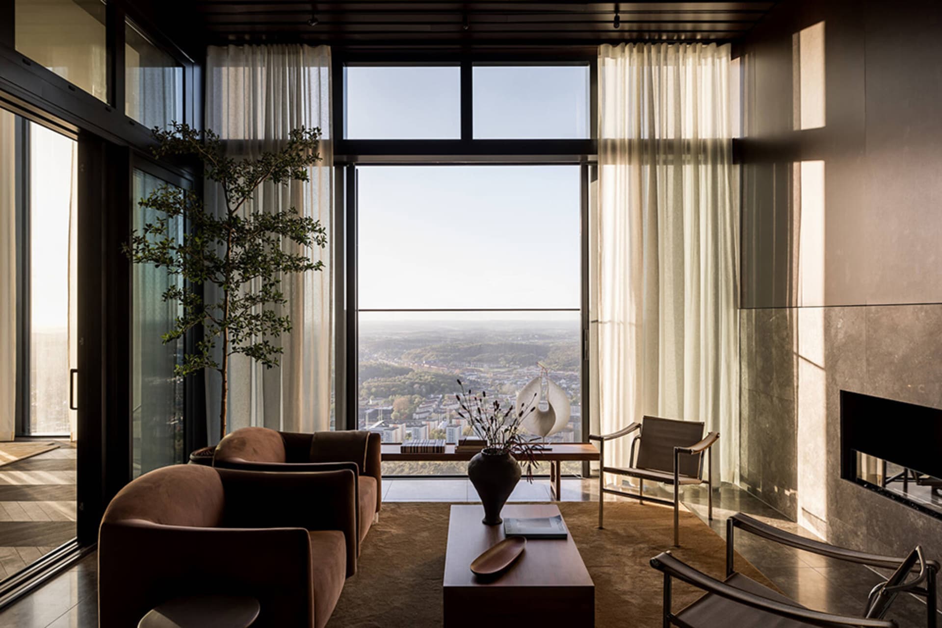 Modern living room with concrete furniture, glass windows, and city view
