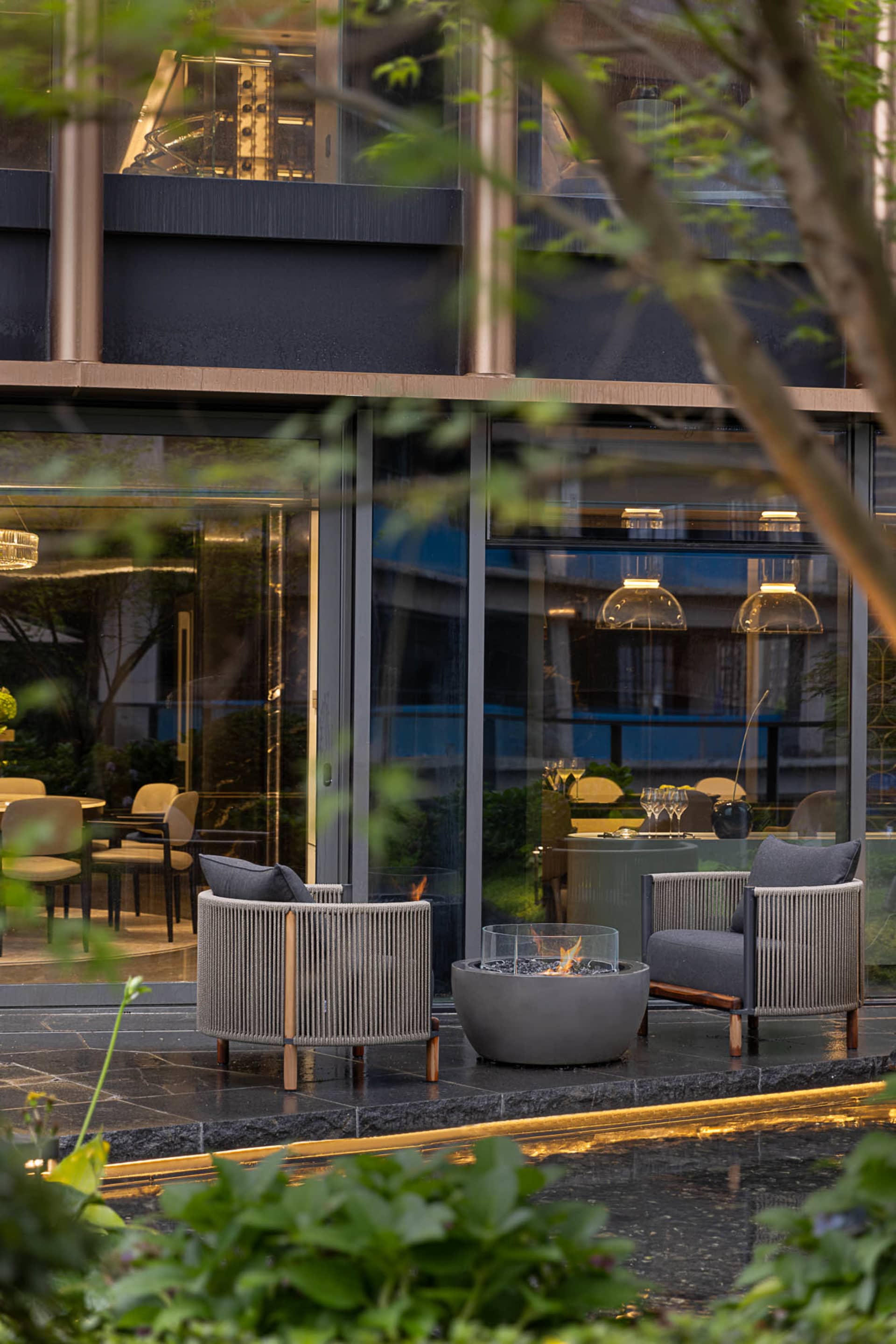 A modern minimalist outdoor seating area featuring concrete furniture and a fire pit.