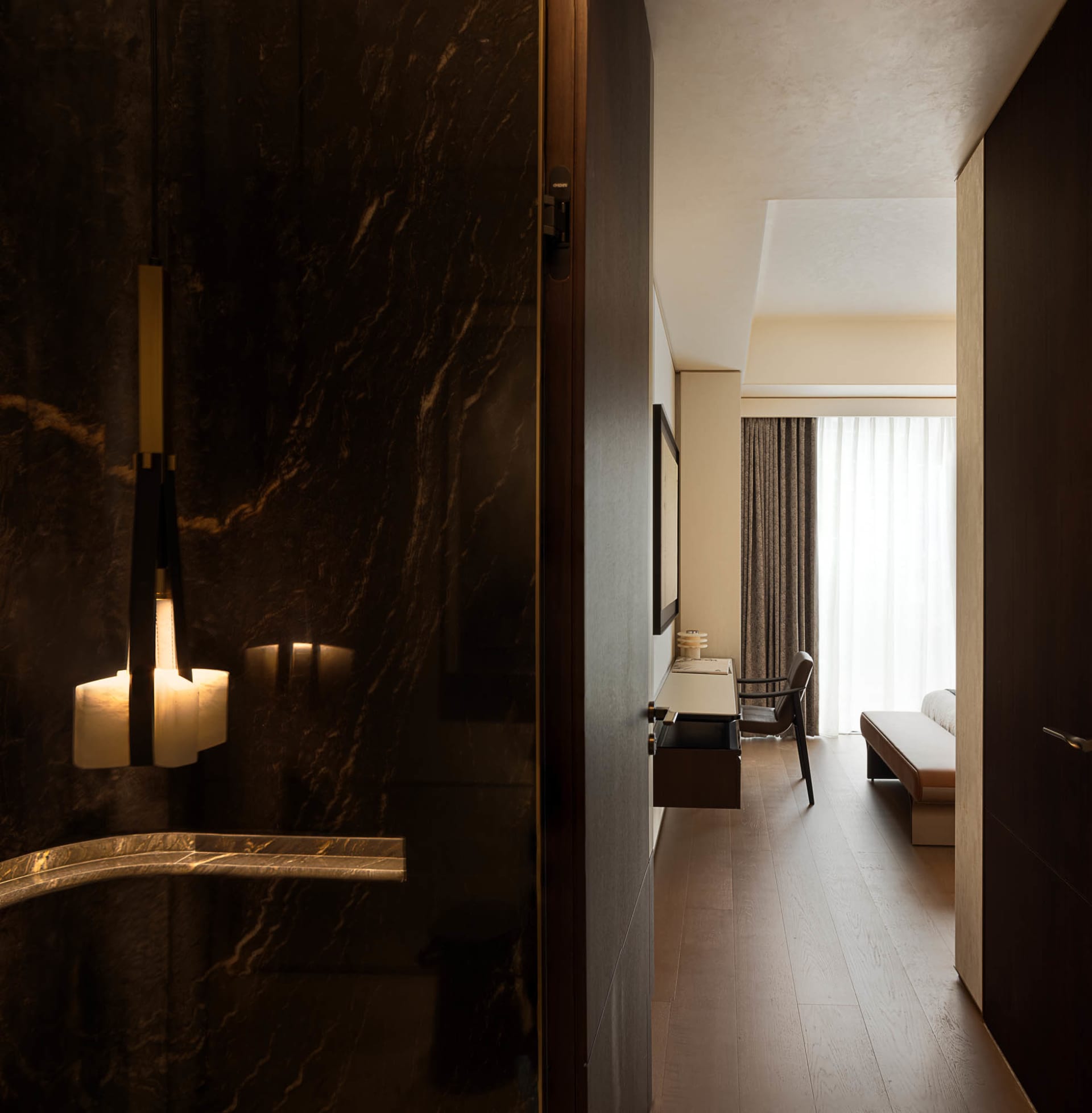 A modern hotel room showcasing marble walls and wooden flooring.