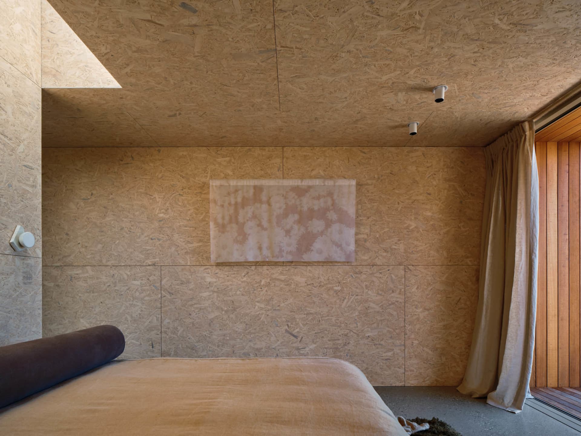 Minimalist bedroom with a bed and OSB board wall