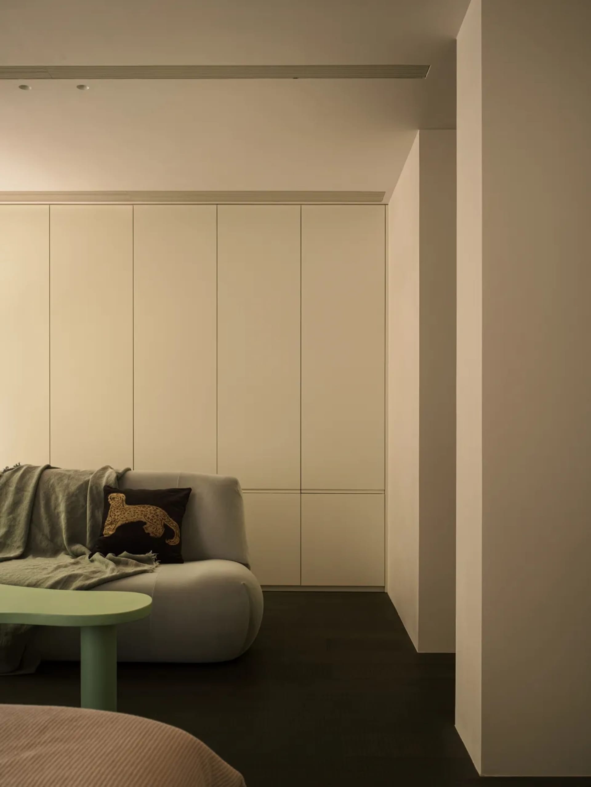 Minimalist living room with a white sofa, green coffee table, and stylish light fixture.