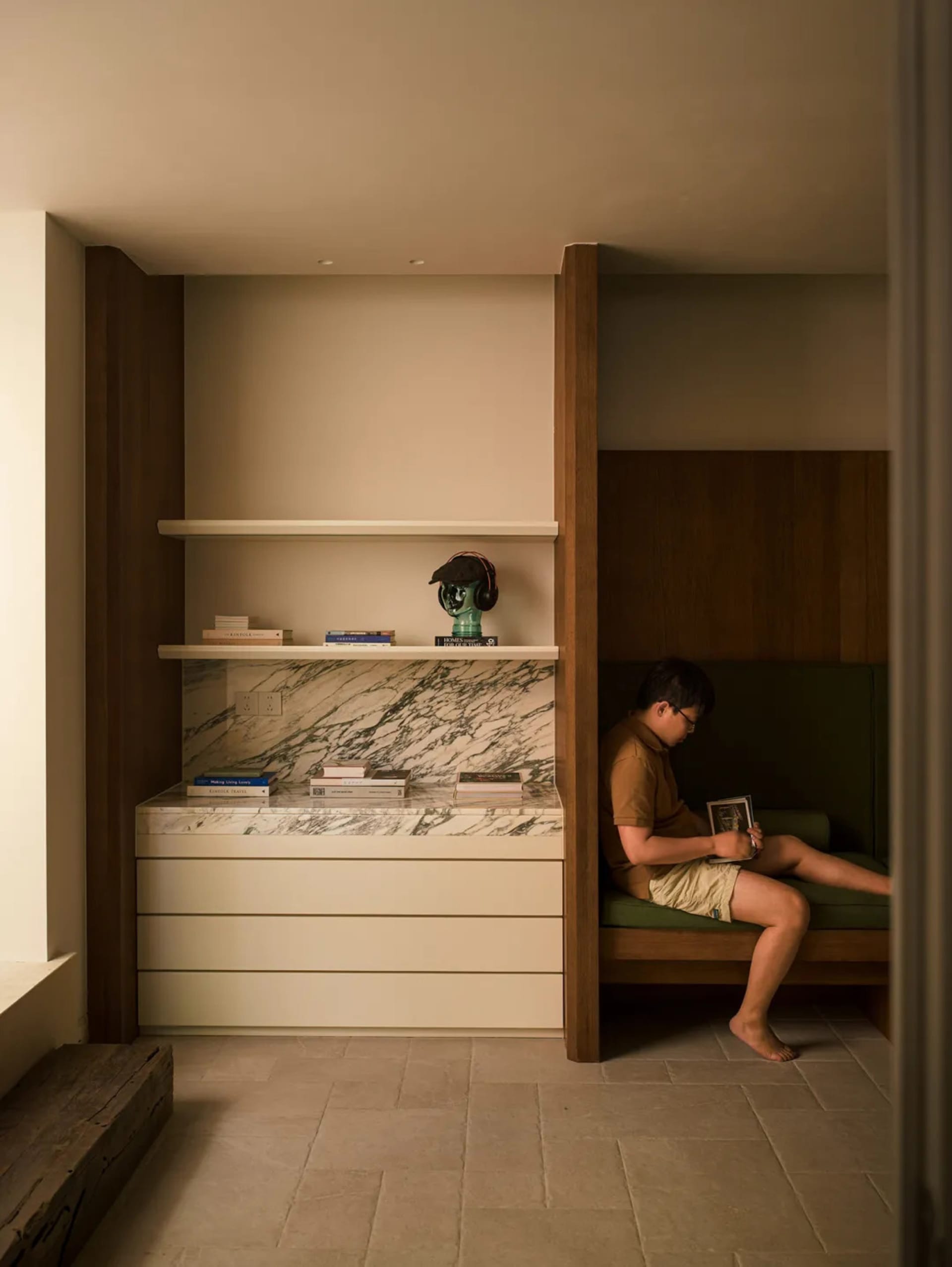 A reading nook with a modern marble and concrete design, featuring a person sitting and reading.
