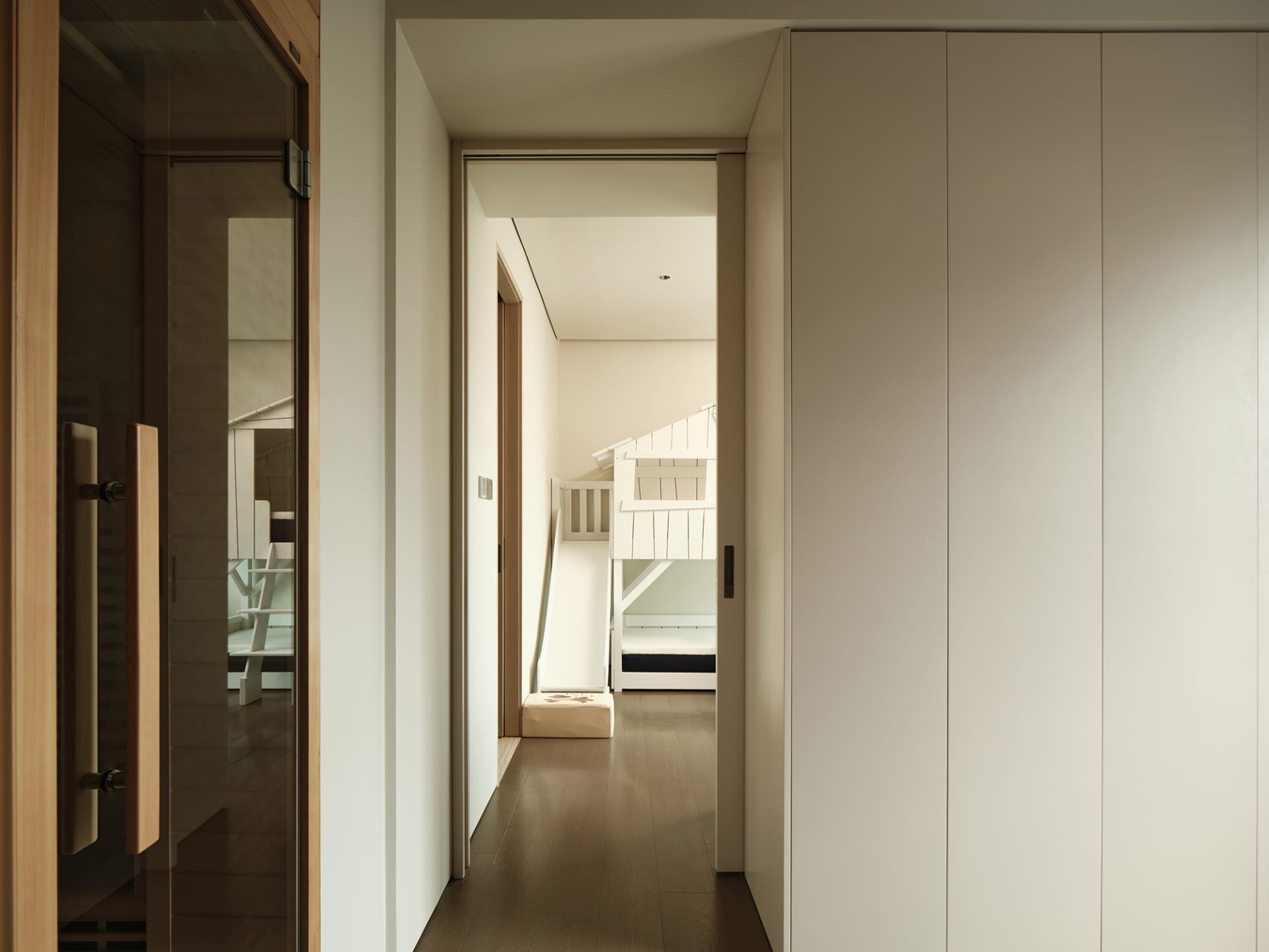 A minimalistic bedroom with white walls and wooden flooring.