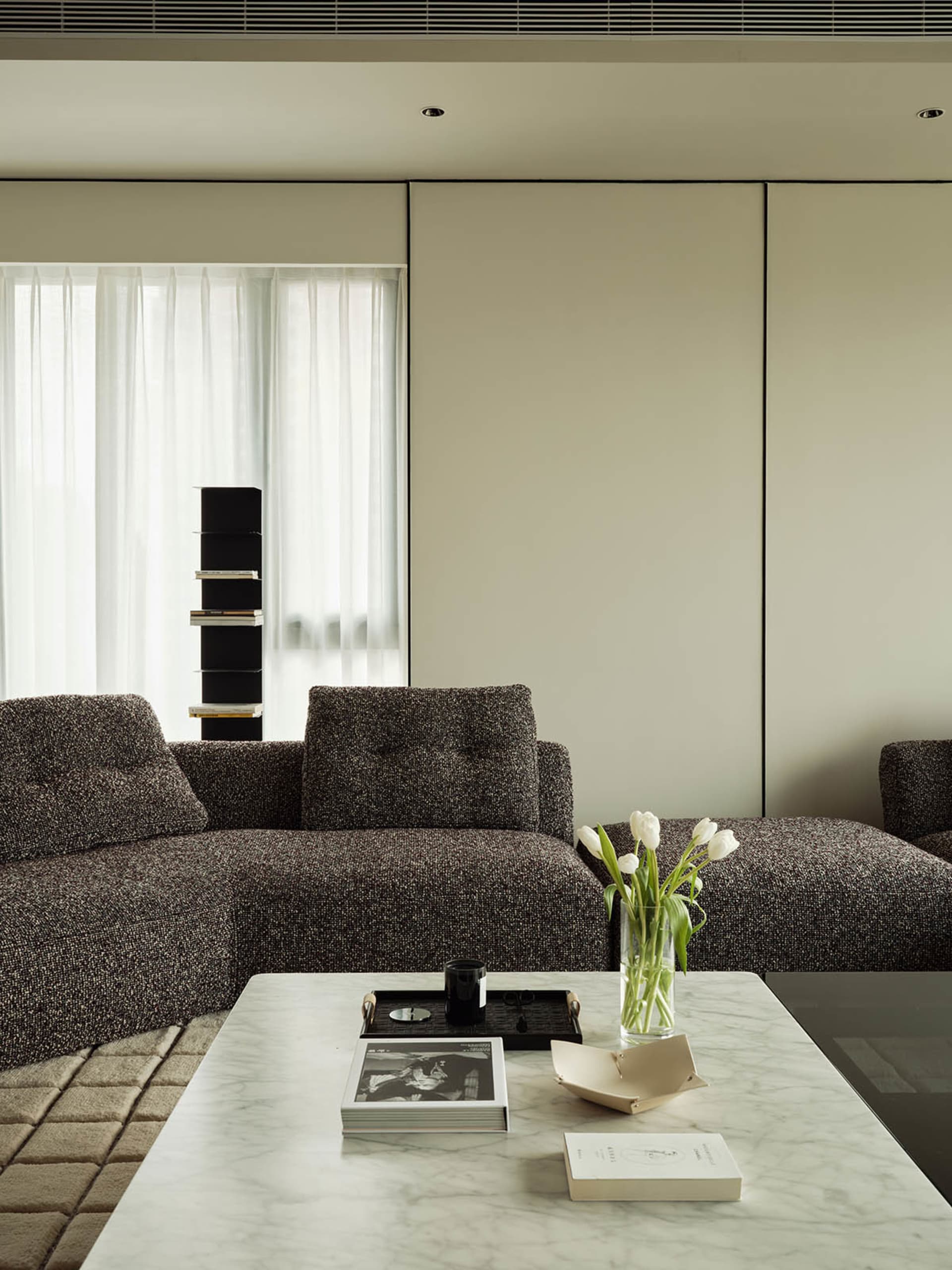 A modern living room with a large sectional sofa and a coffee table with a vase of tulips and books.