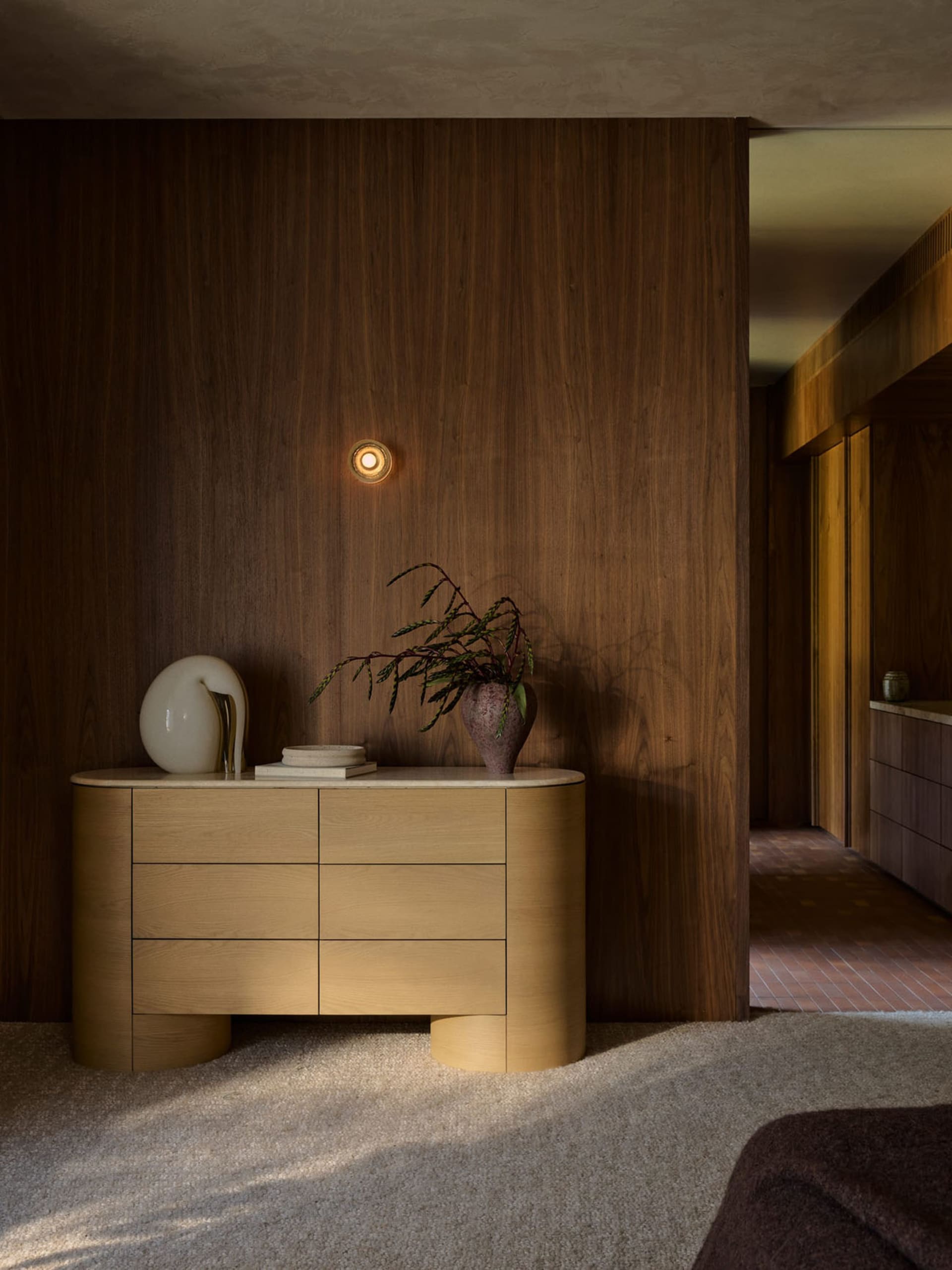 A modern living room featuring wooden furniture and a plant.