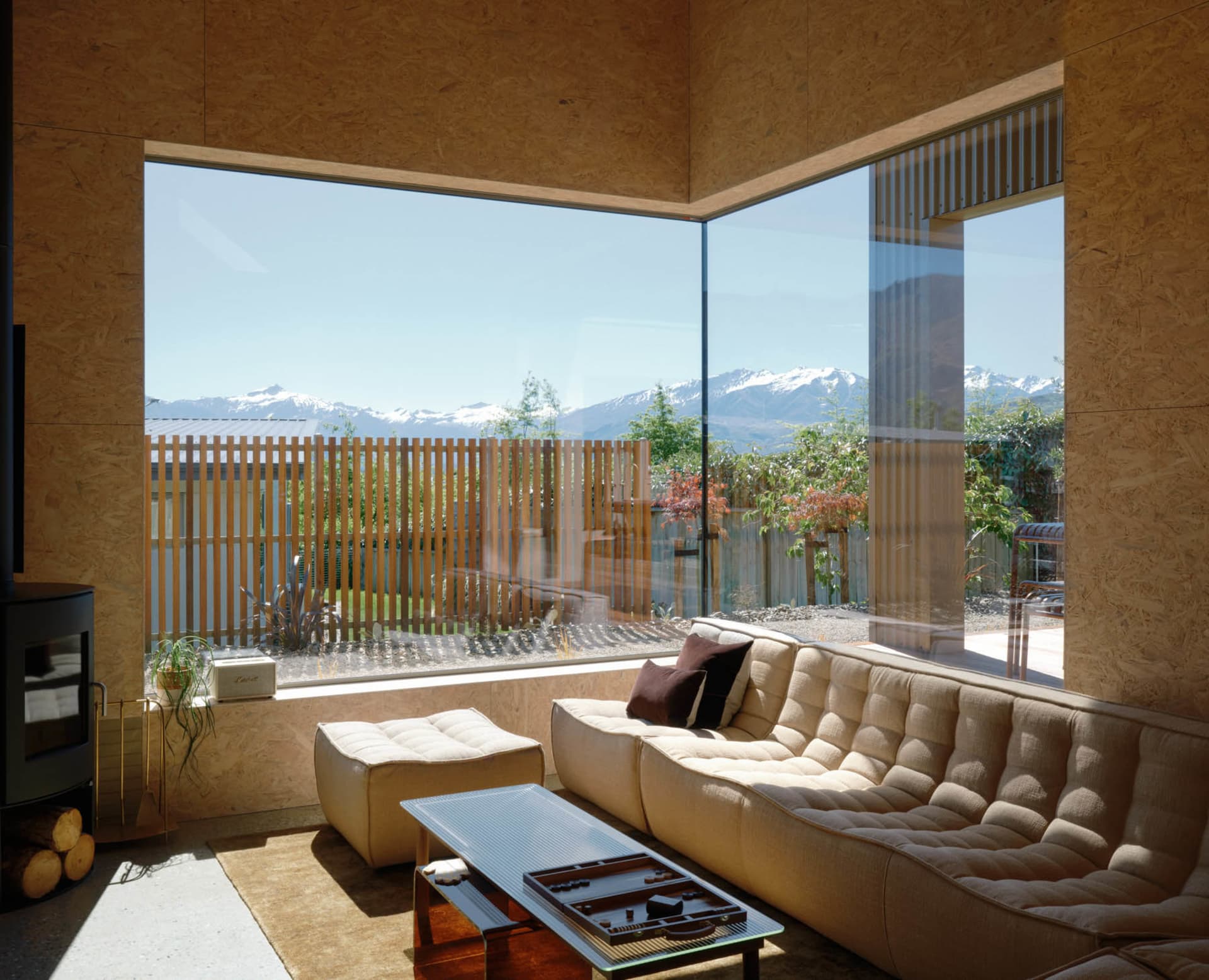 Modern minimalist living room with large glass window overlooking mountains, featuring a comfortable sofa with cushions, a lo