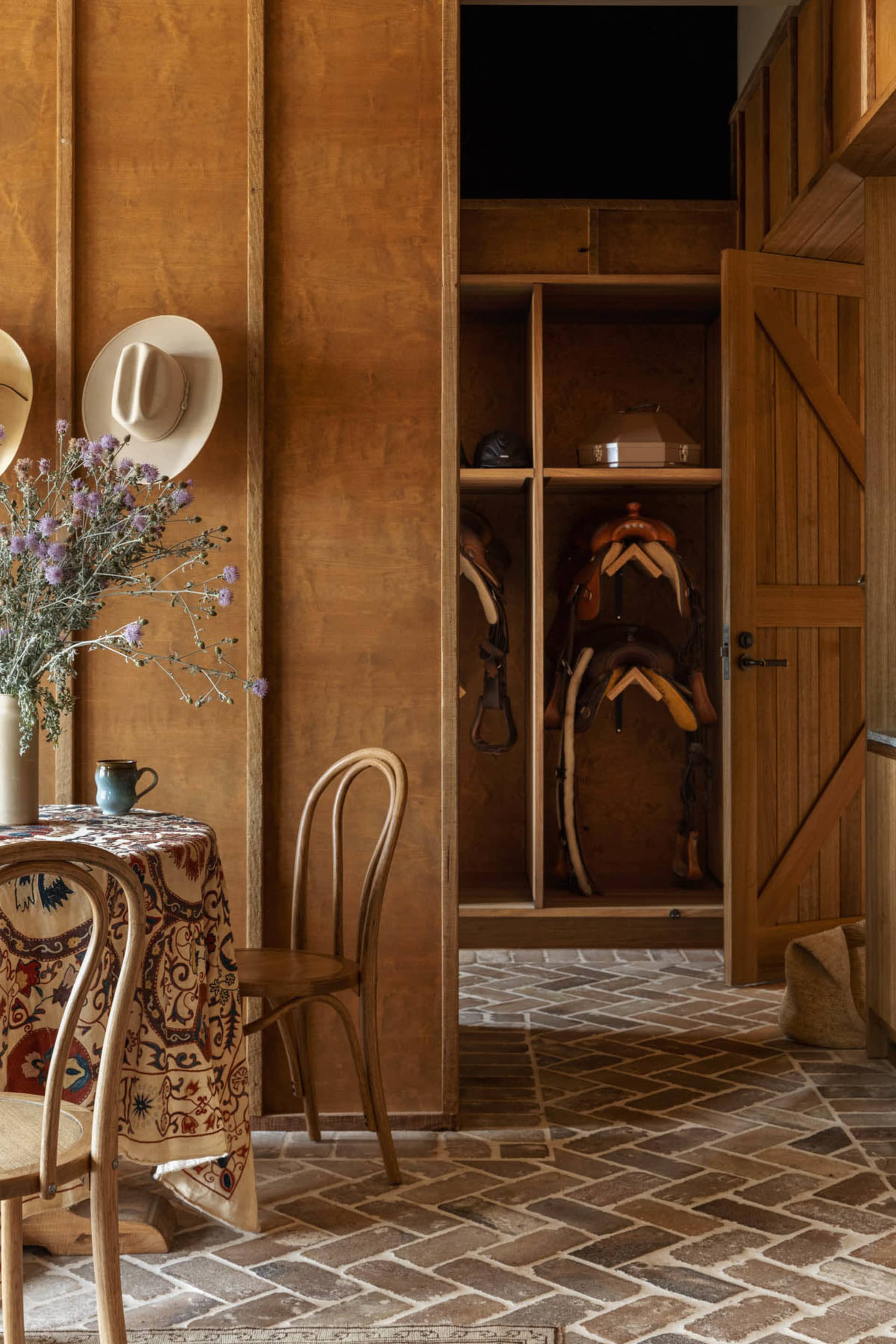 A rustic storage room with wooden furniture and horse equipment hanging on the wall.