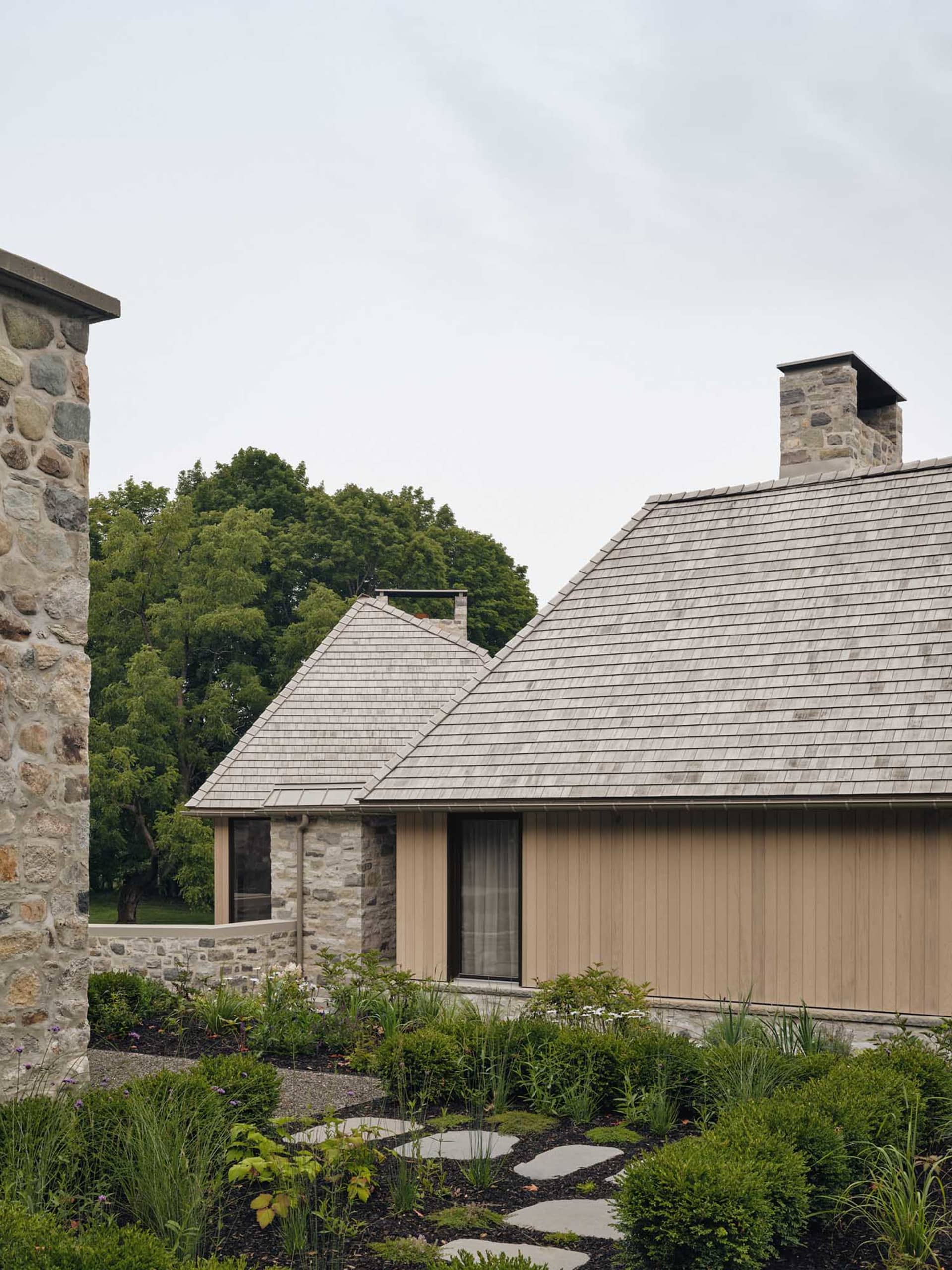 A modern residential exterior featuring wood and stone elements.