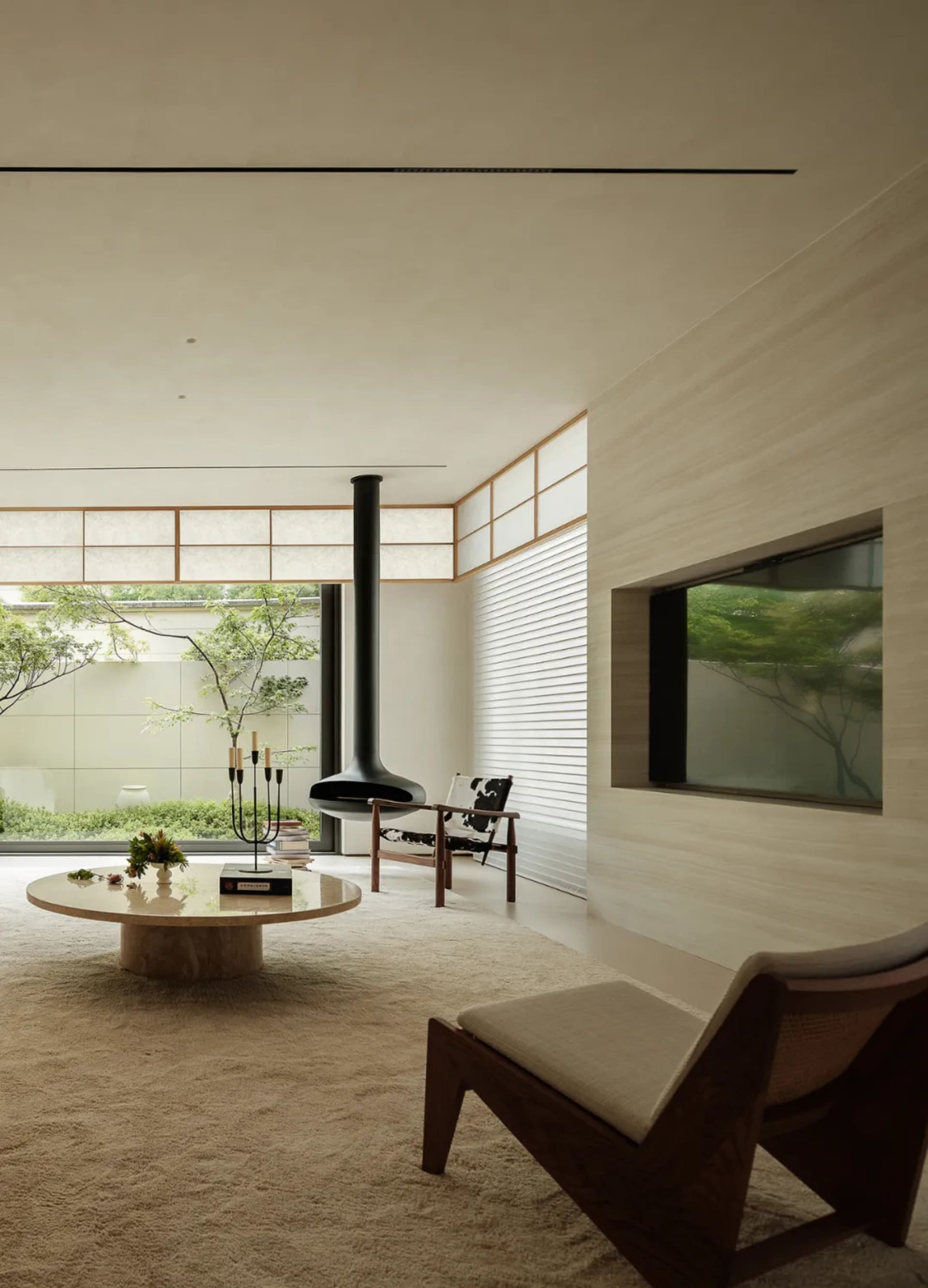 Contemporary living room with minimalist design, featuring wooden paneling, glass coffee table, and concrete flooring.