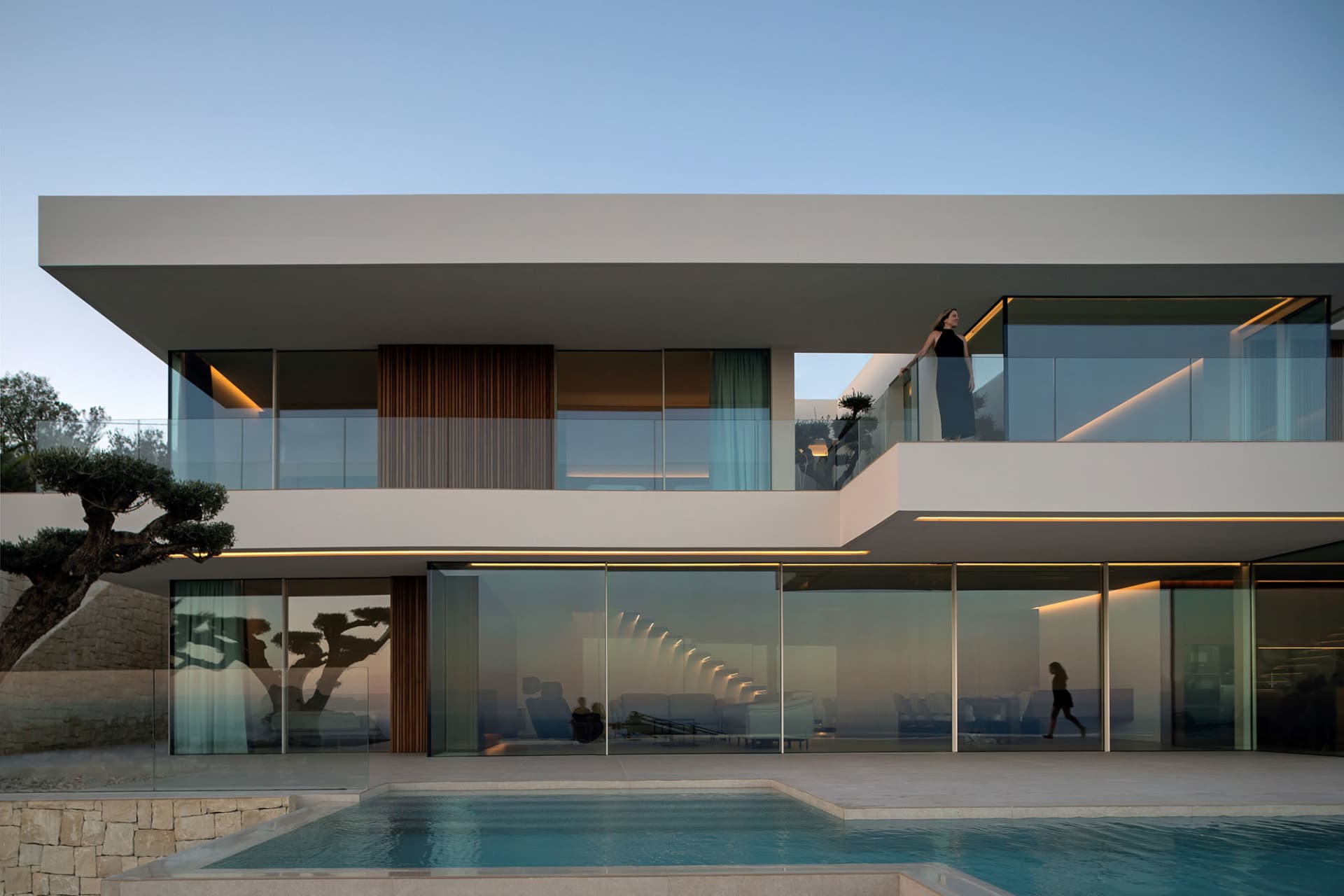 A modern residential villa featuring a glass and concrete exterior with a swimming pool.