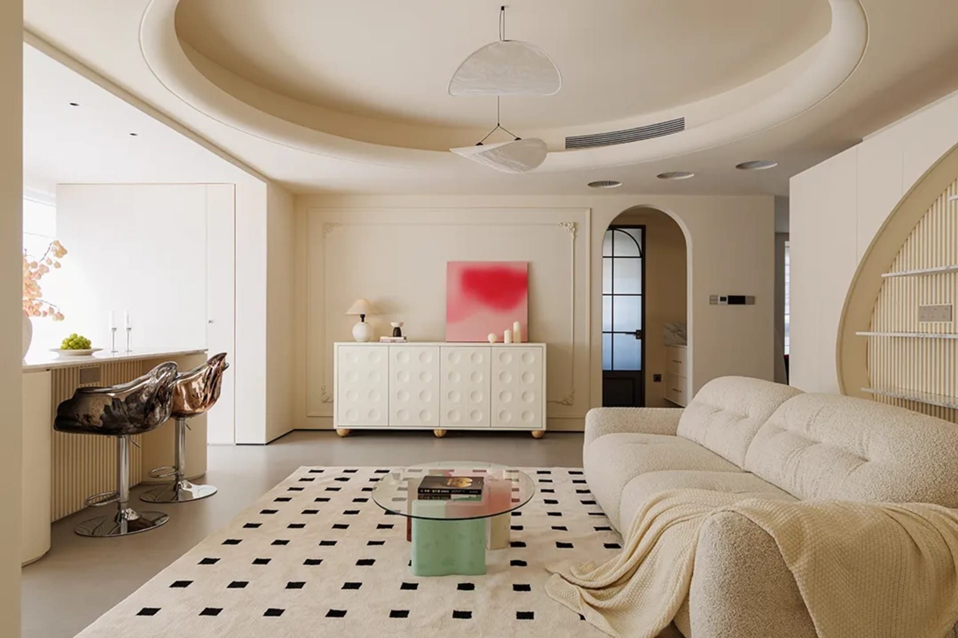 Modern living room featuring a comfortable beige sofa, a round glass coffee table, and a bold pink artwork on a textured wall
