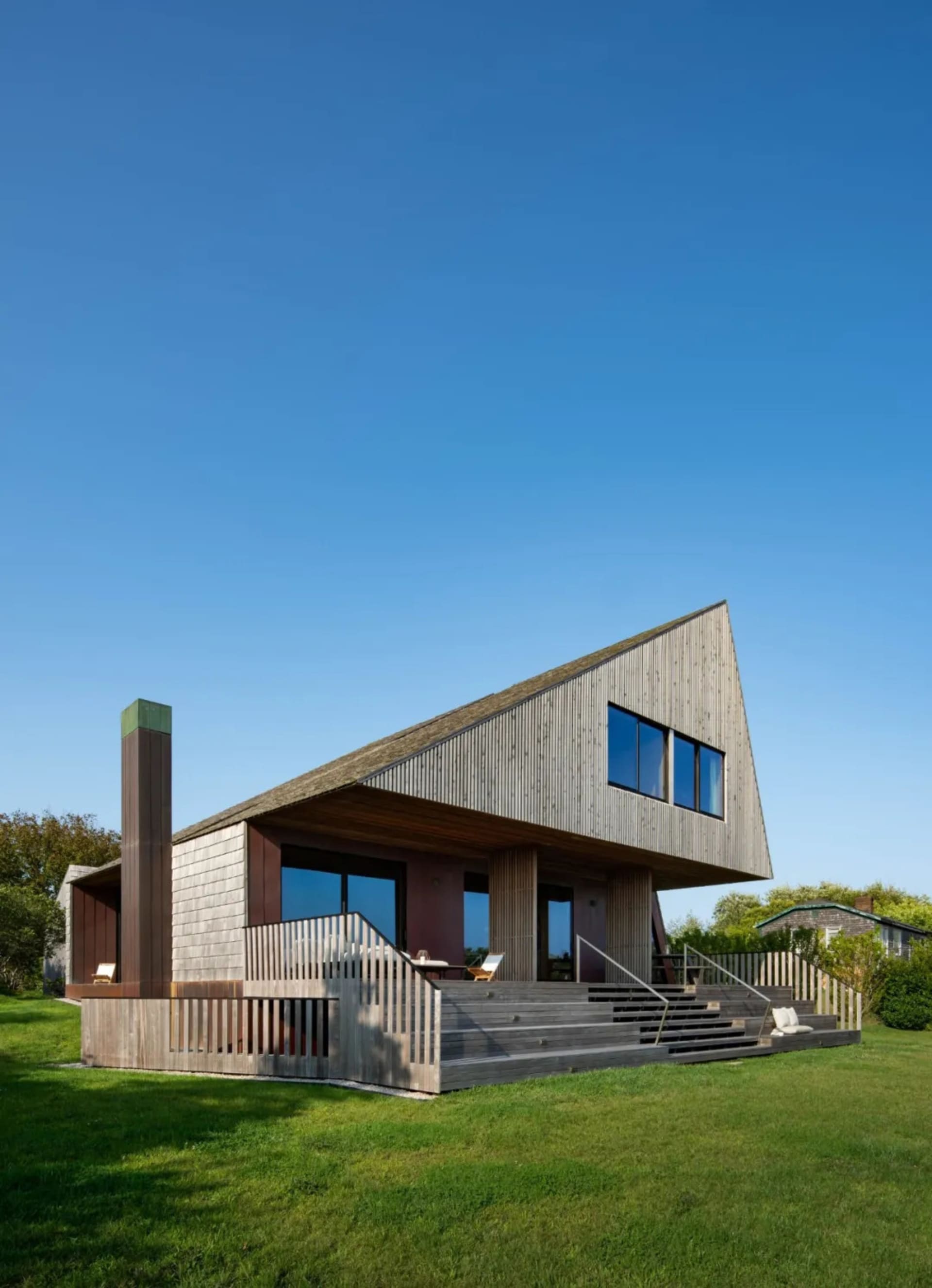 A modern wooden residential house with a triangular roof and glass windows.