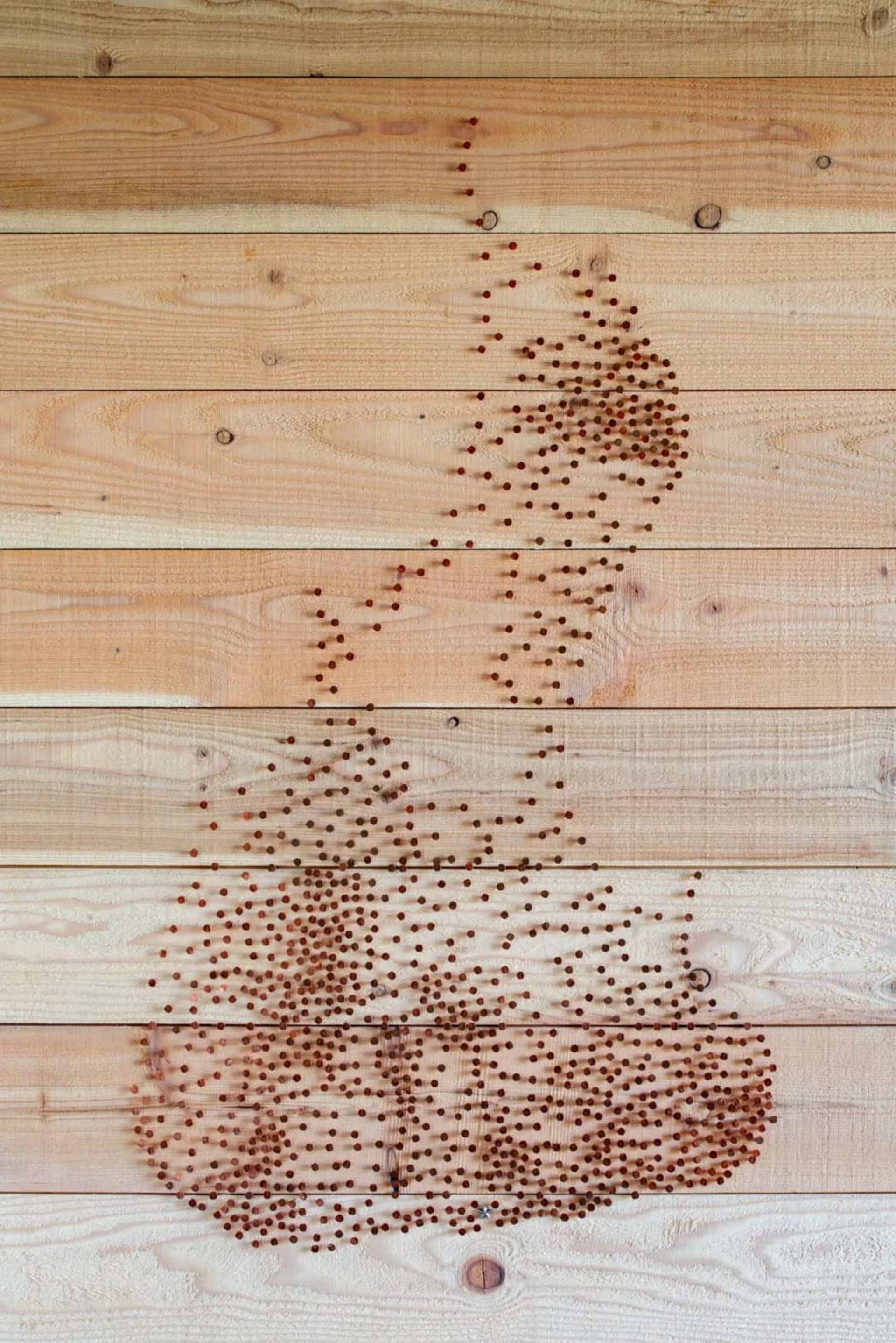 A piece of industrial-style string art made from wooden beads arranged on a wooden surface to form the shape of a coffee cup
