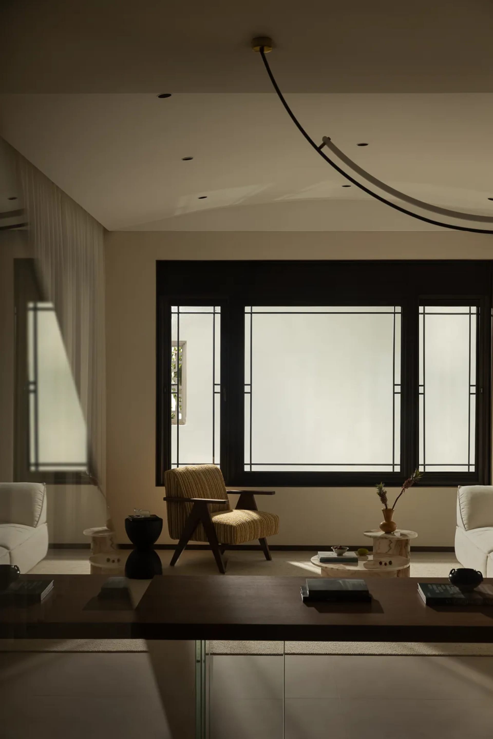 A minimalist living room with wooden elements and large windows.