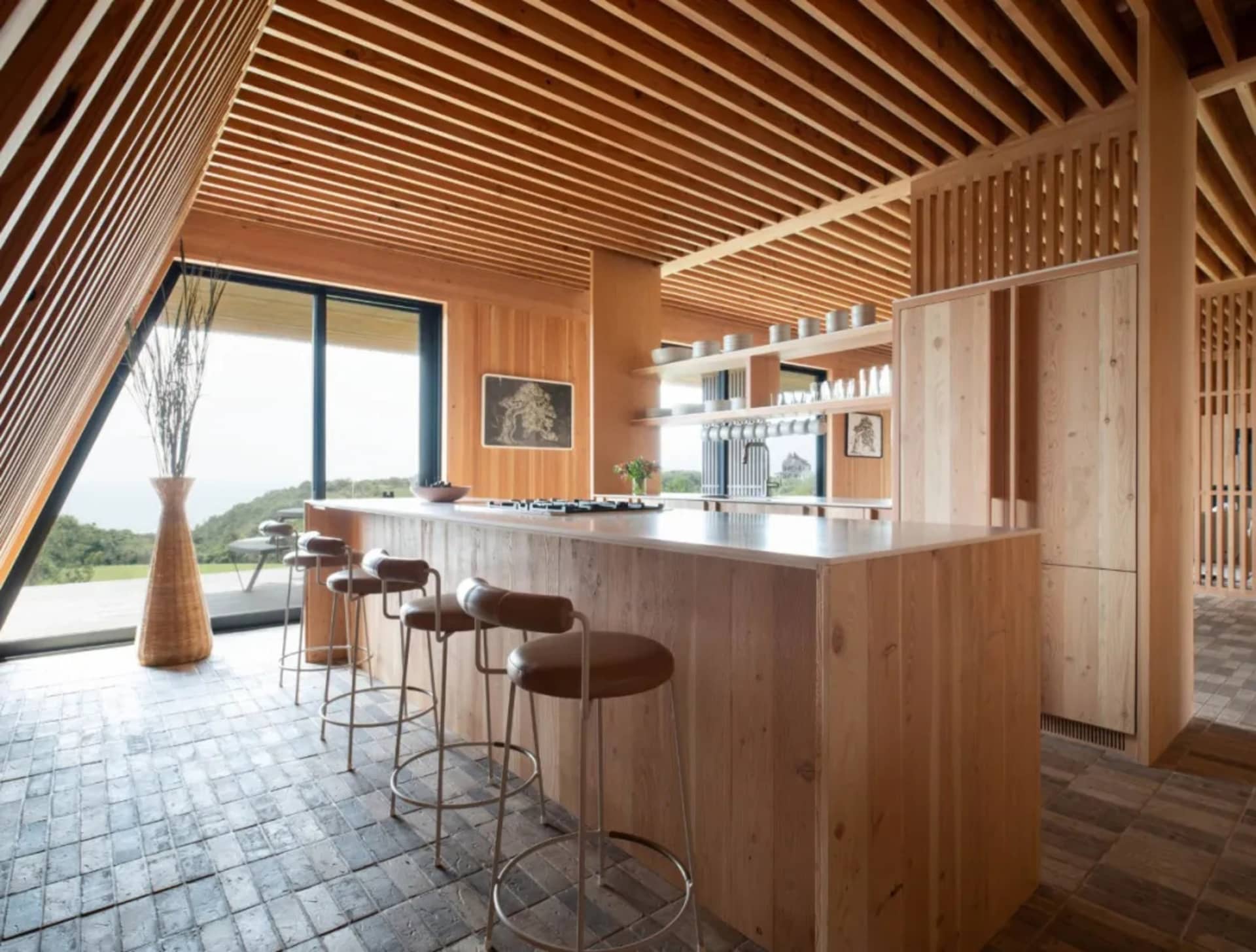 Modern kitchen with wooden island, stools, and open shelving.