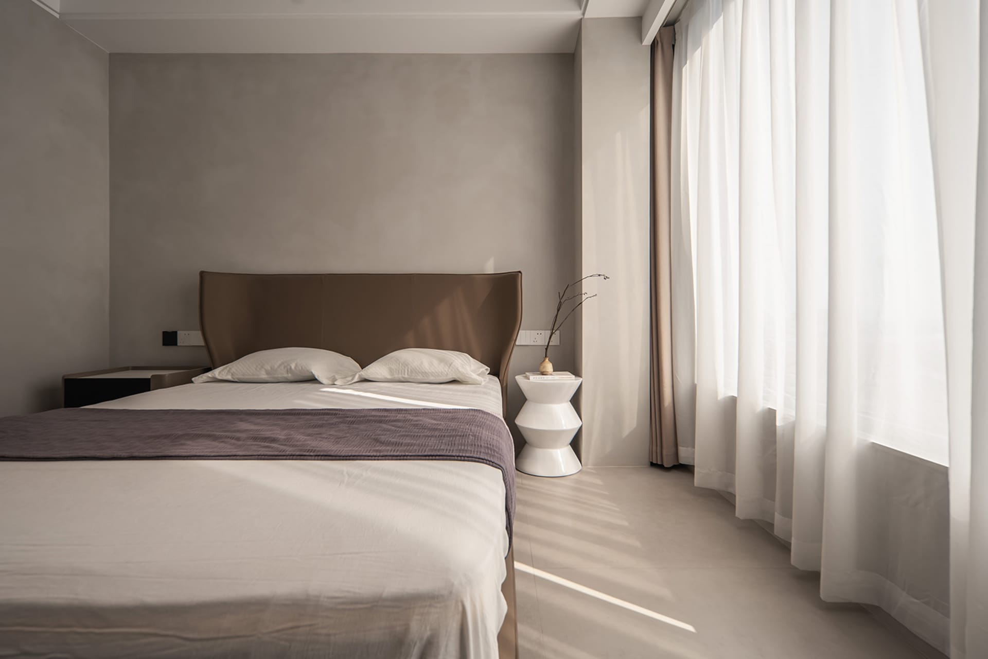 Modern minimalist bedroom featuring a sleek white bed with a glass and metal headboard, clean lines, and a cozy atmosphere cr