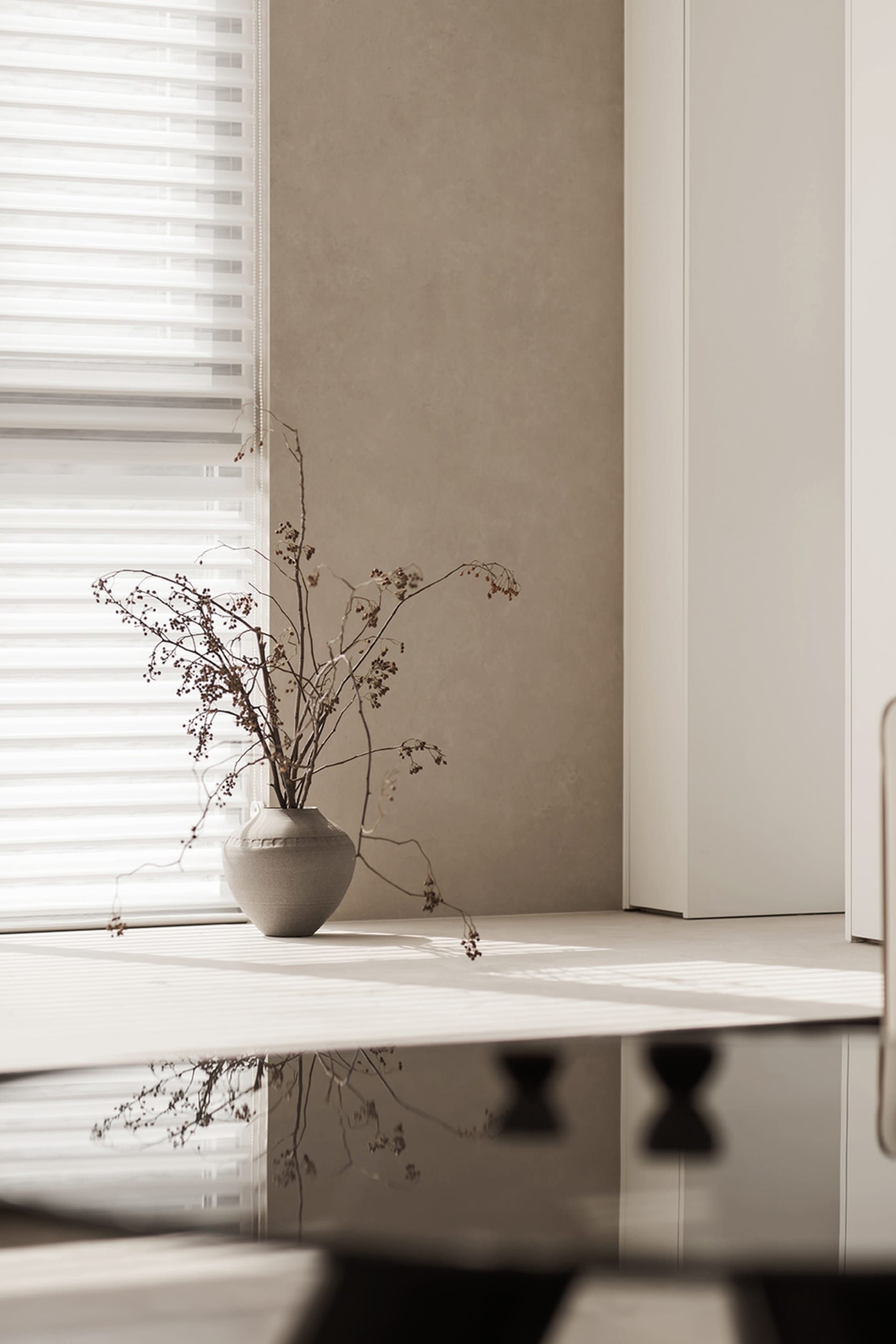 A minimalist interior space with concrete elements and a vase of dried flowers.