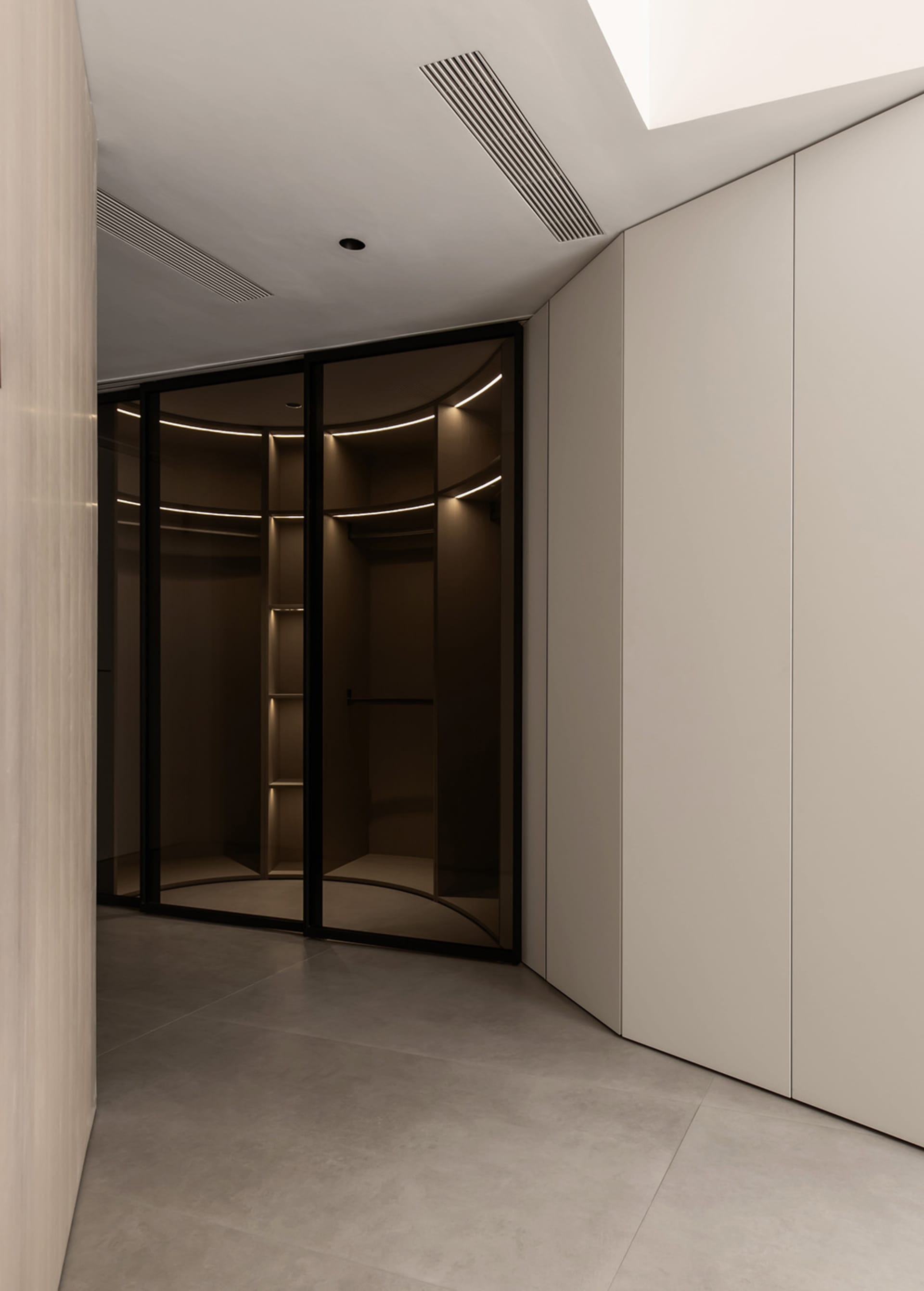 Modern modular closet with glass panels and lighting inside.