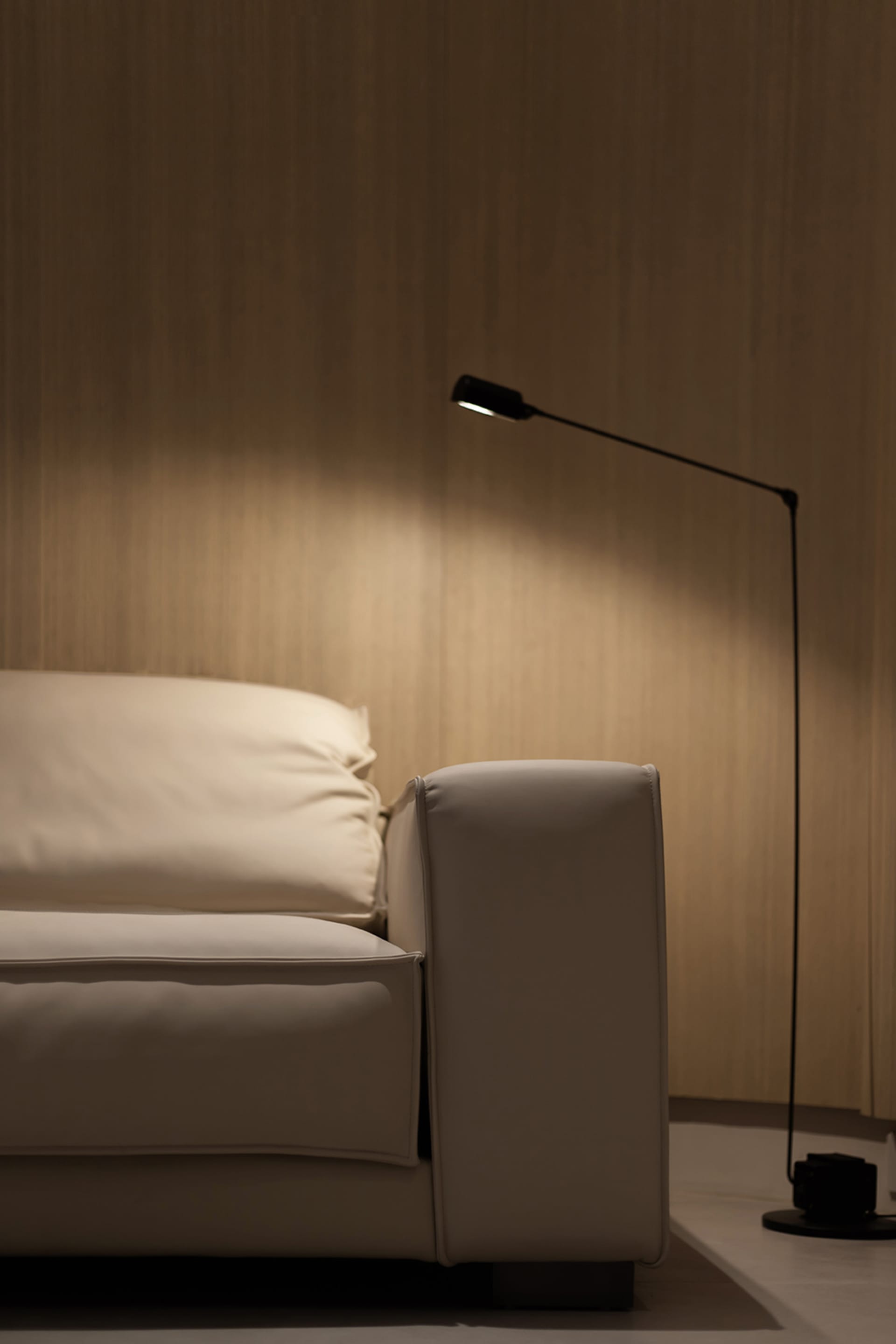 一張現代白色沙發旁邊擺放著立燈，位於明亮的室內空間。