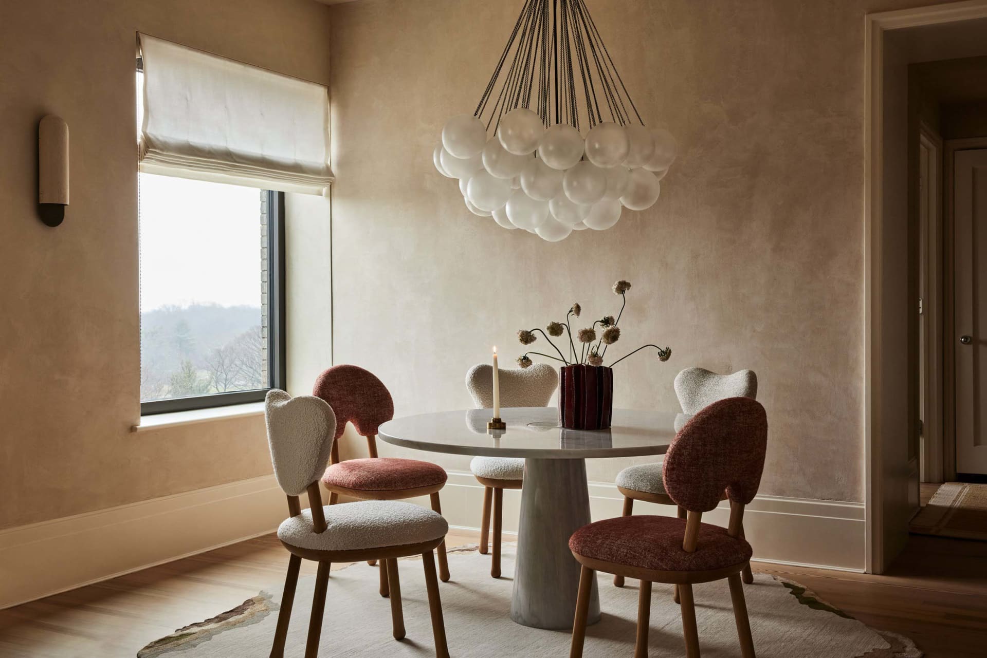 A warmly lit dining room featuring wooden furniture and a round table with a stone pedestal base.