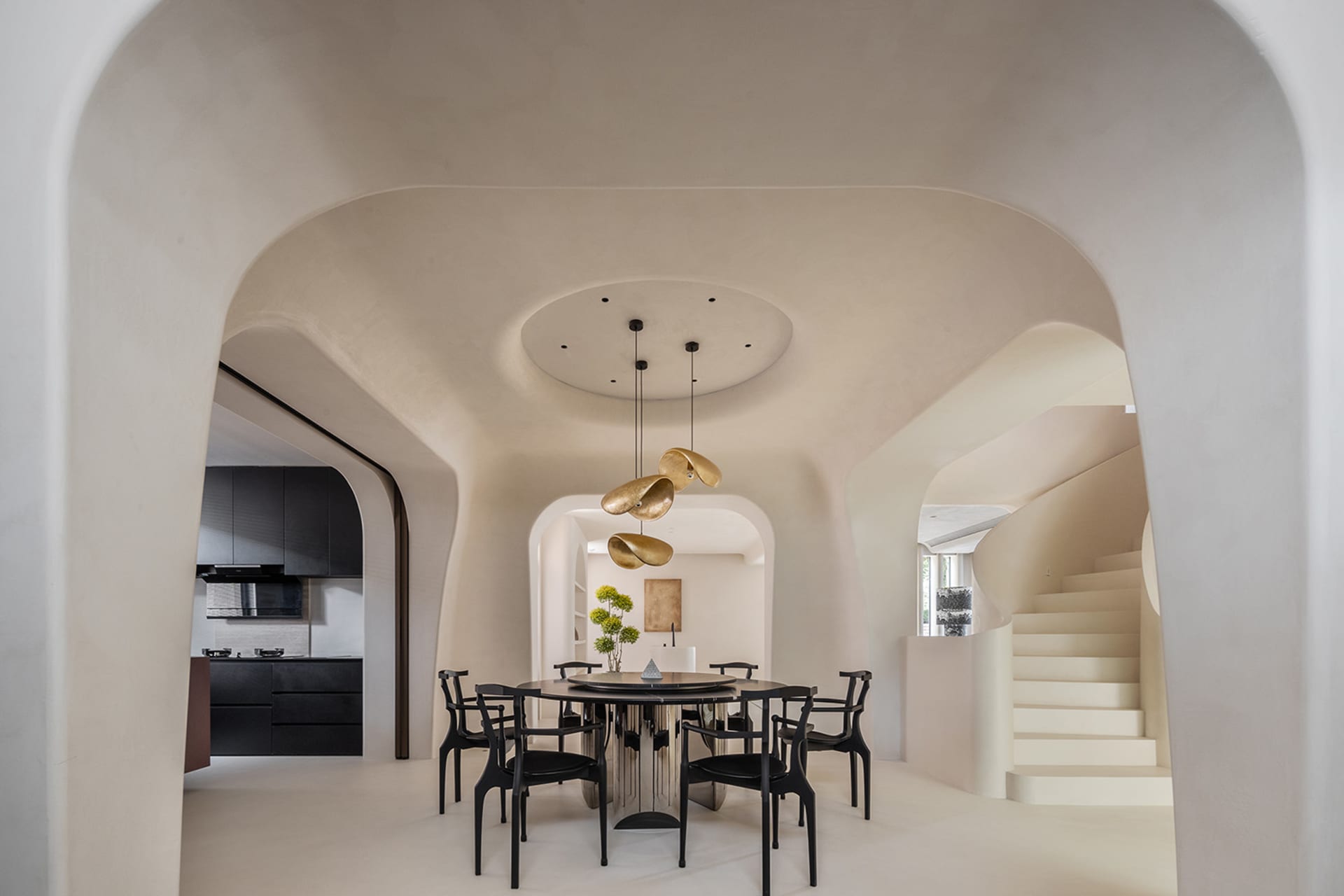 A modern dining room with concrete flooring, a circular table, and black chairs.