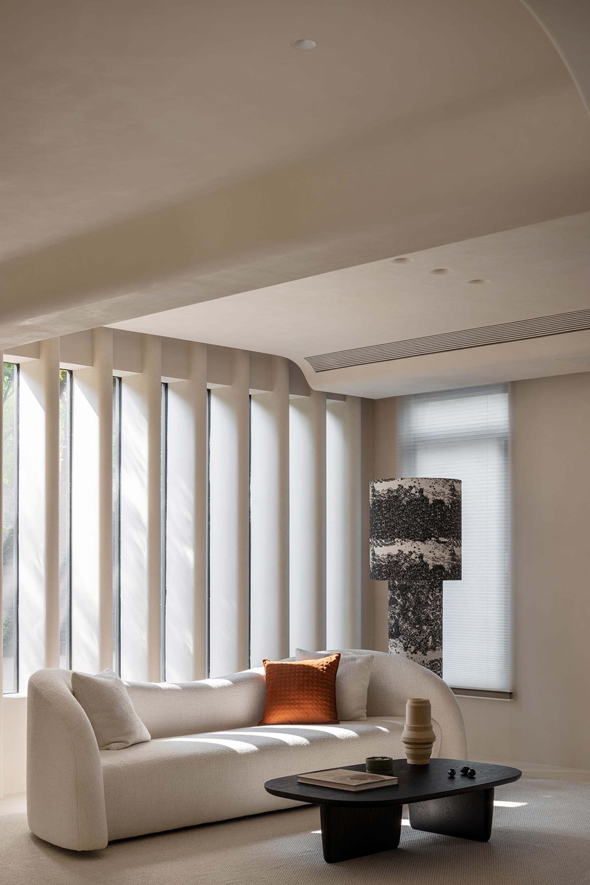 Modern minimalist living room with fabric sofa, glass window, and metal table.