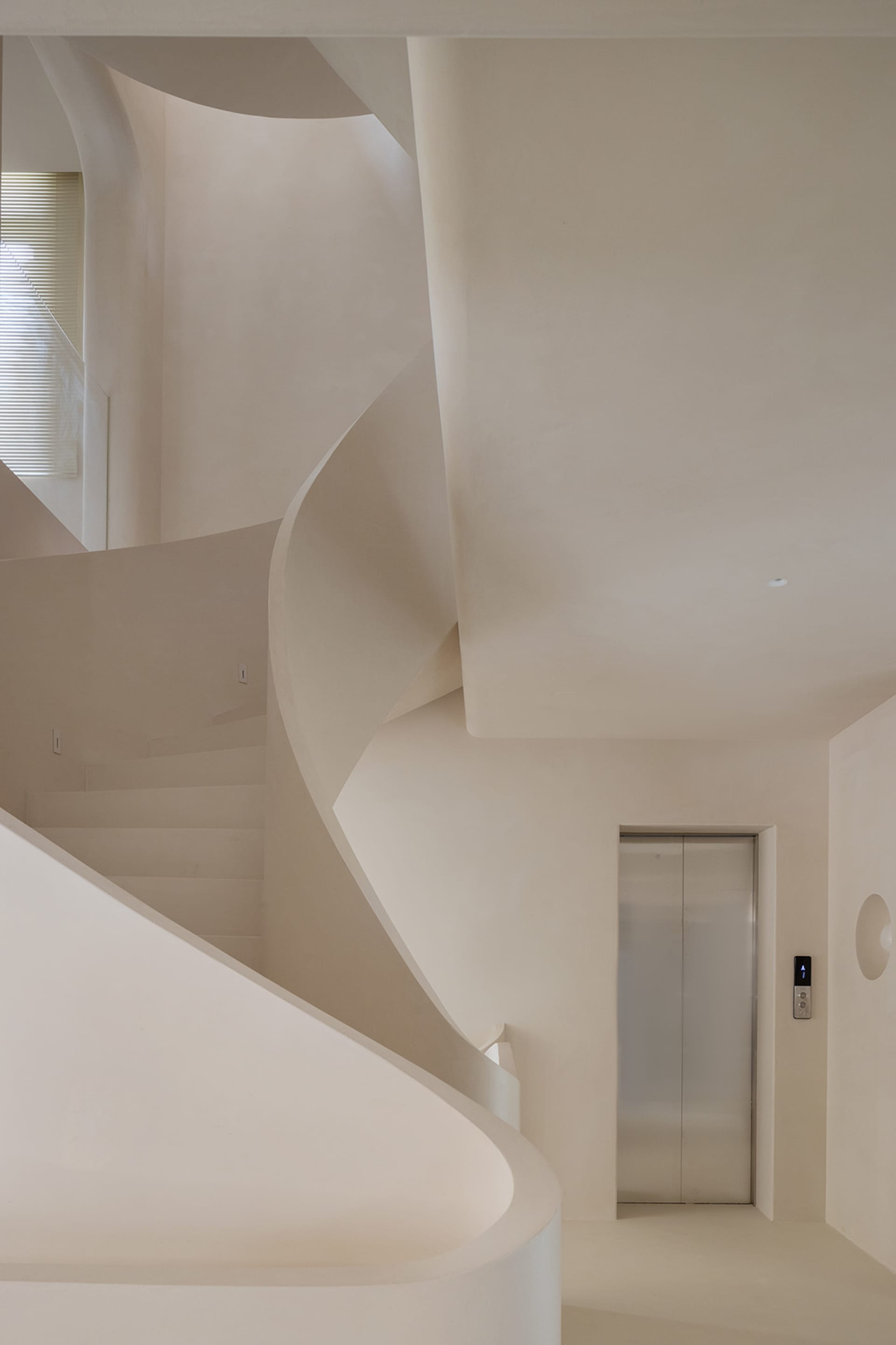 A modern, minimalist spiral staircase made of concrete
