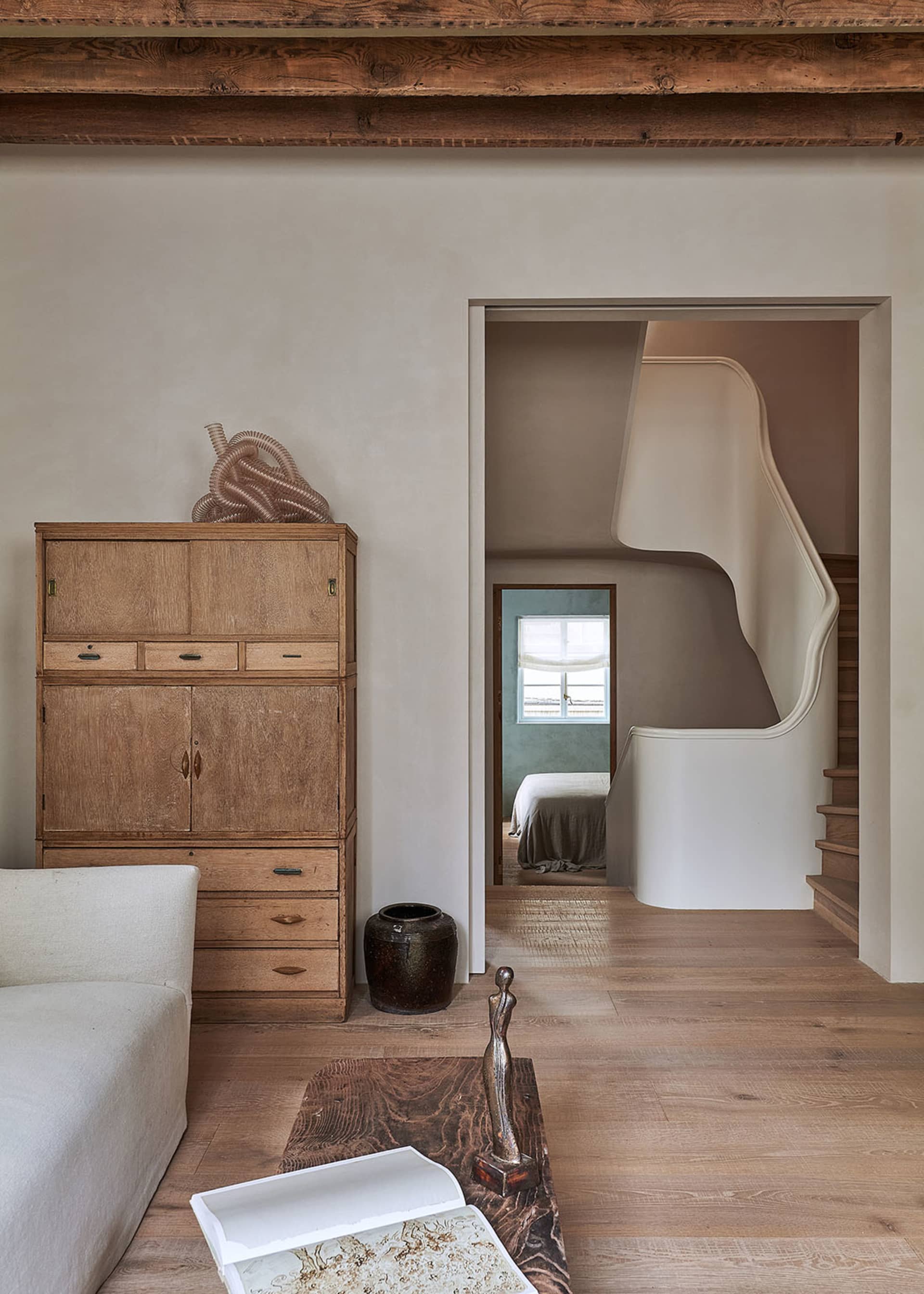 A minimalist living room featuring wood furniture and natural light.