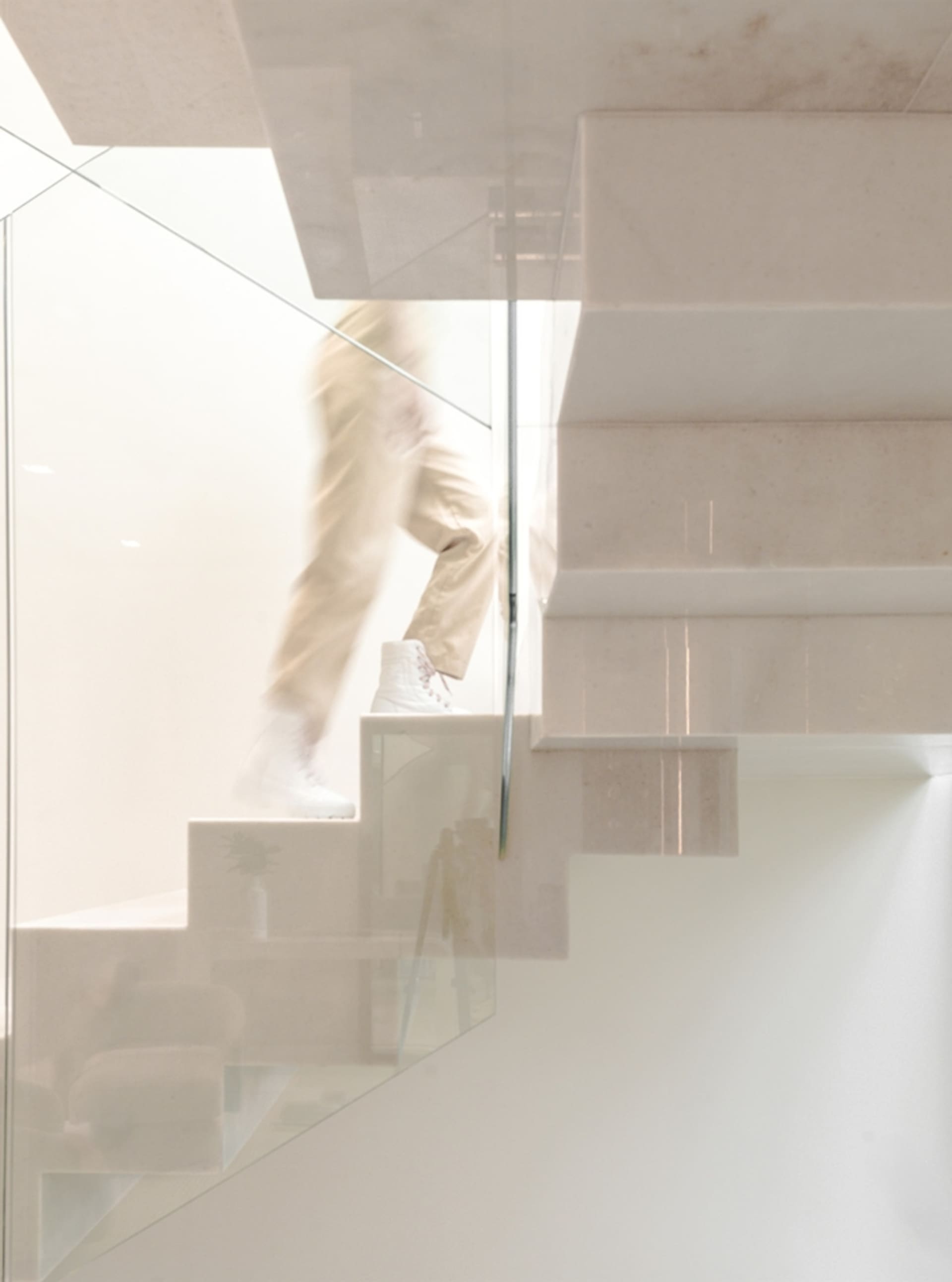 A minimalist staircase with white concrete and glass railings.