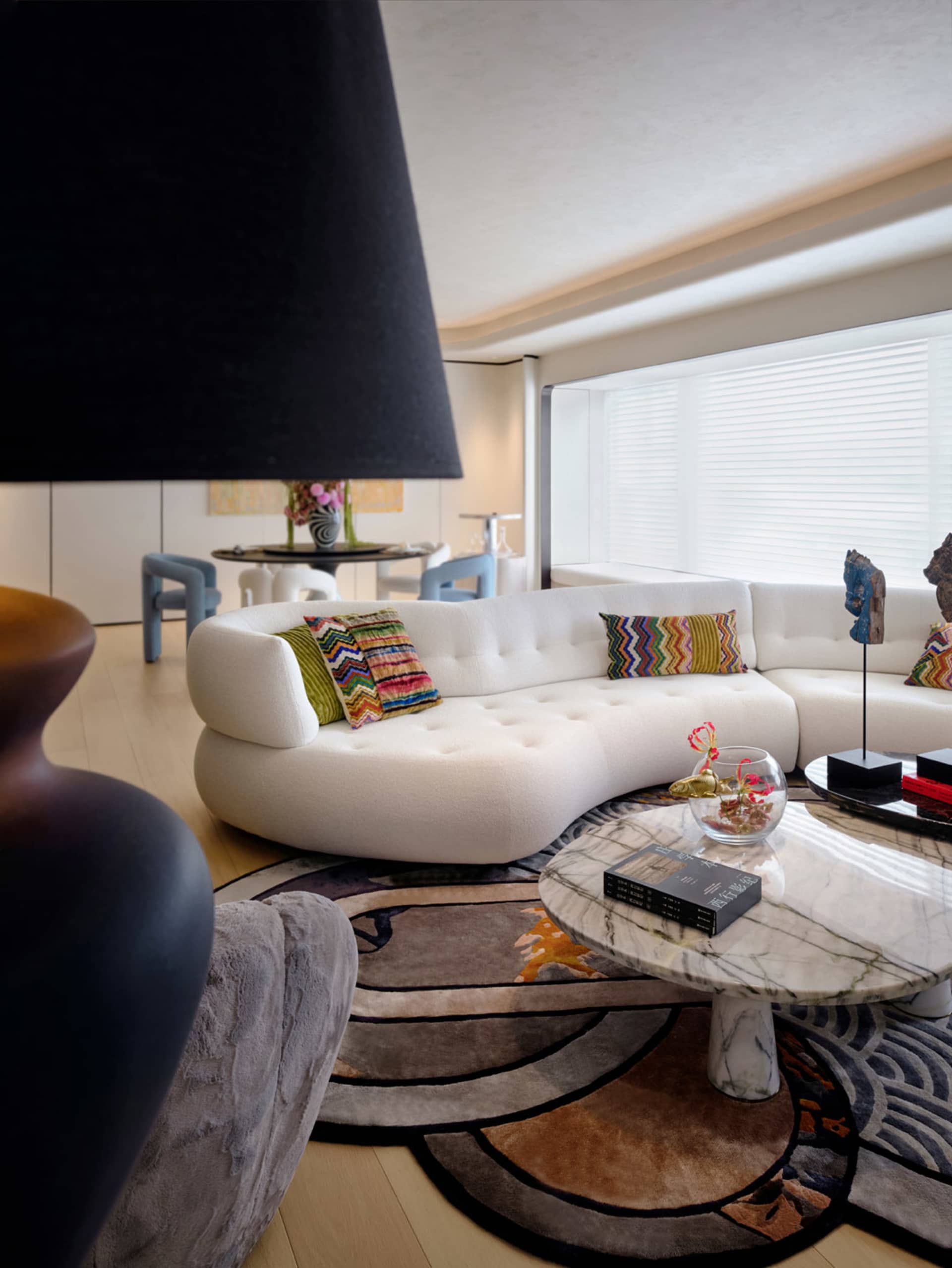 Modern living room featuring a white leather couch, colorful throw pillows, and a round coffee table.