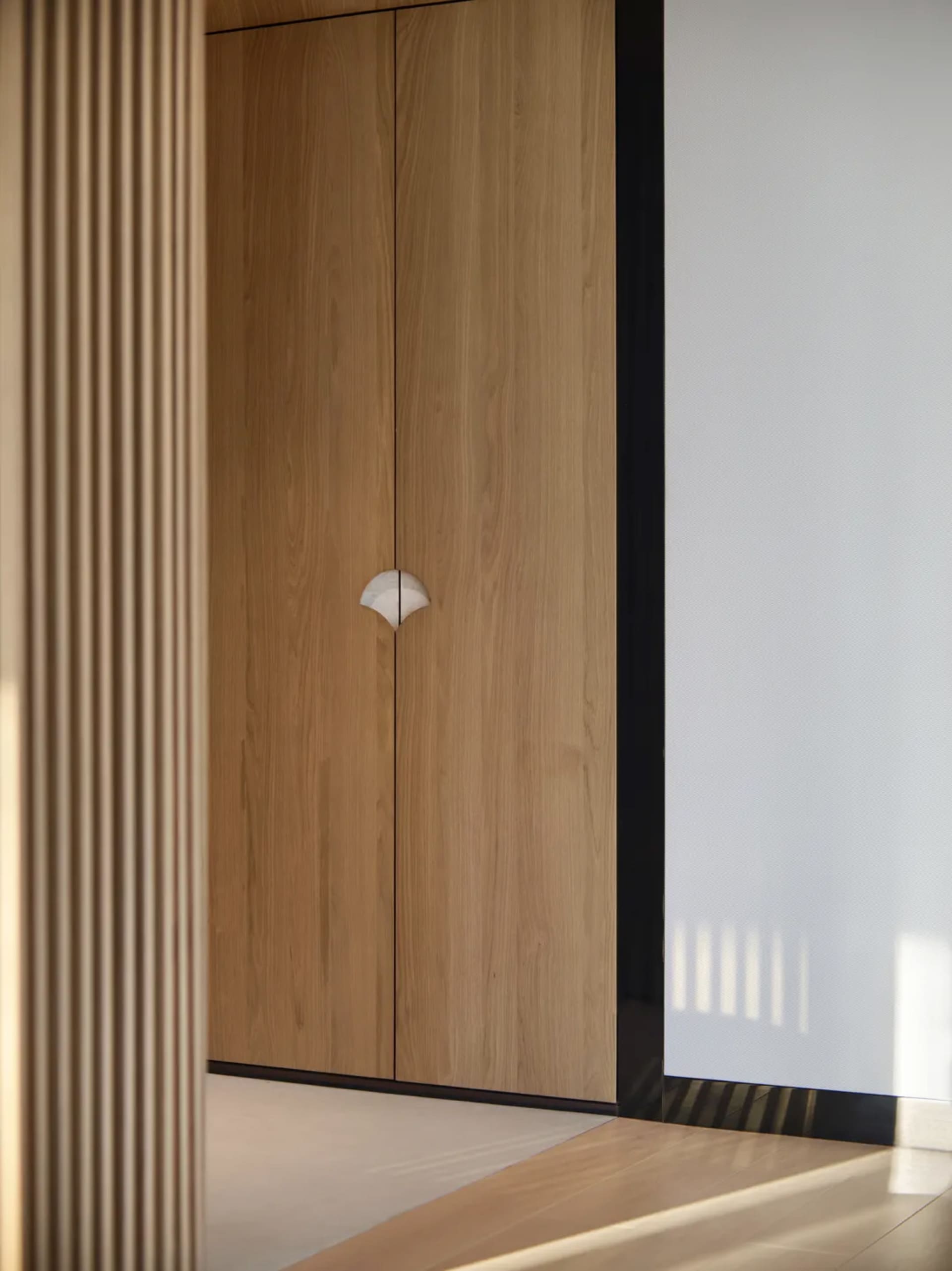 A modern minimalist wooden cabinet with a unique white circular handle.