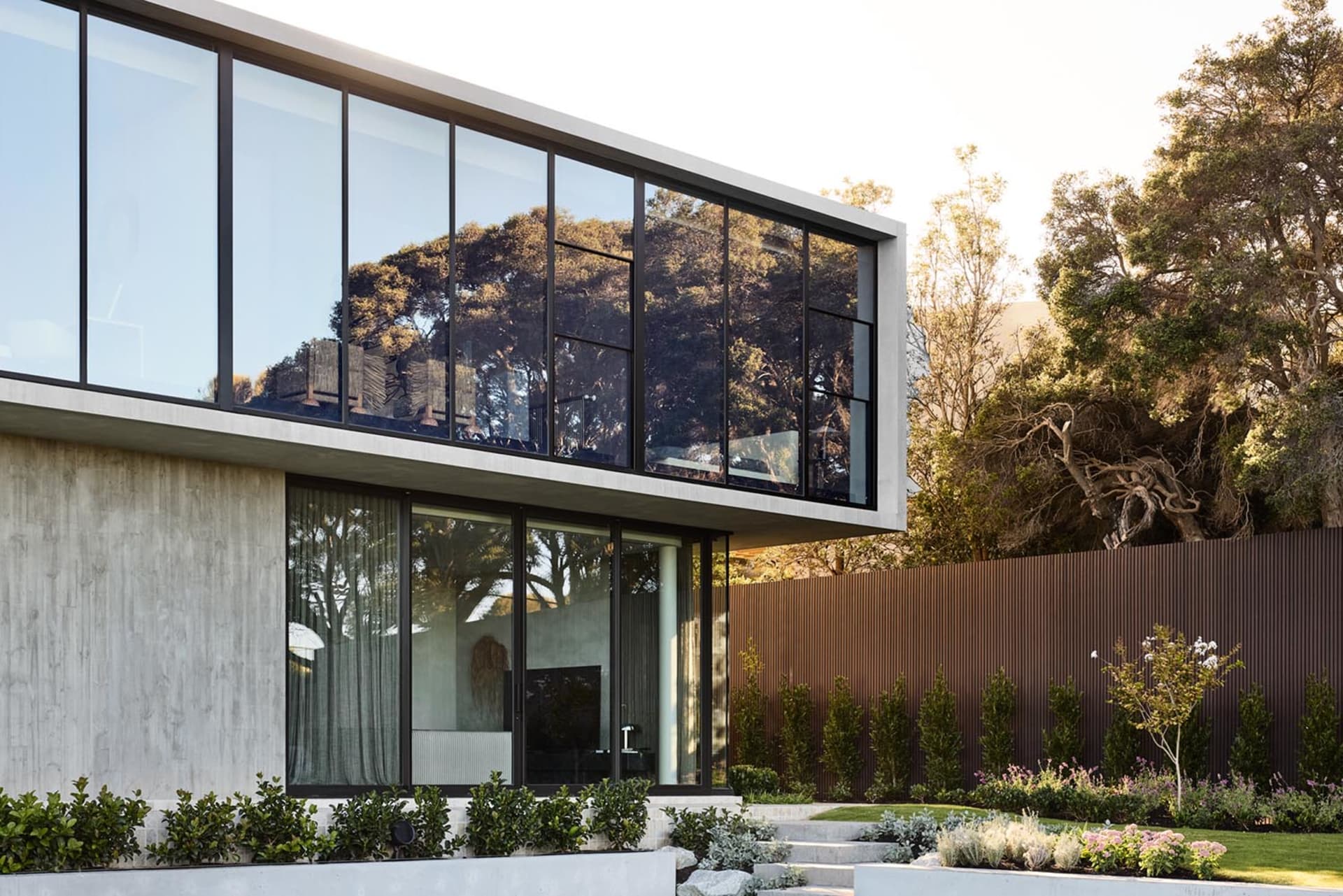 Modern residential home with large glass windows and concrete exterior.