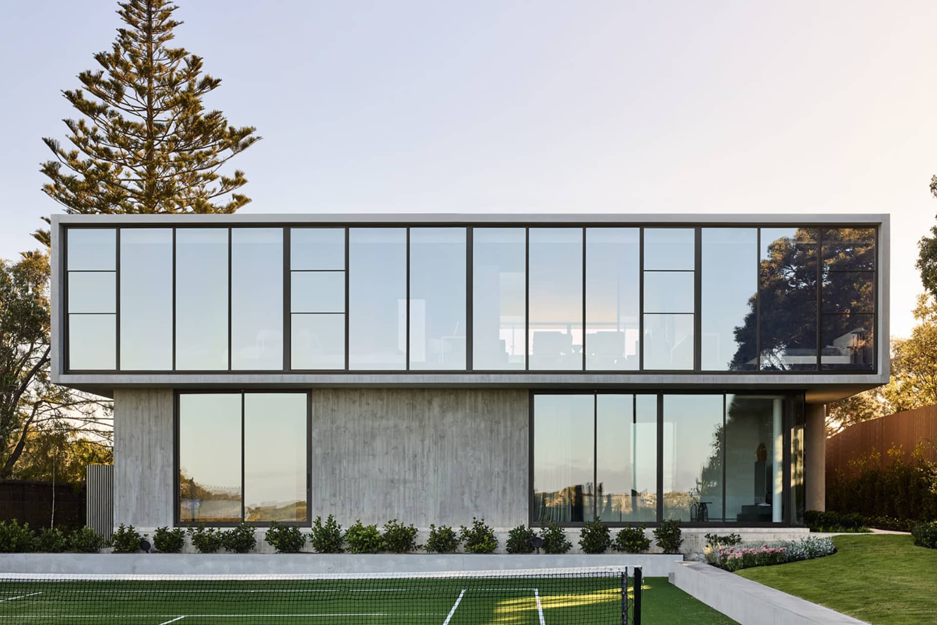 A modern residential house featuring a concrete exterior and large glass windows.