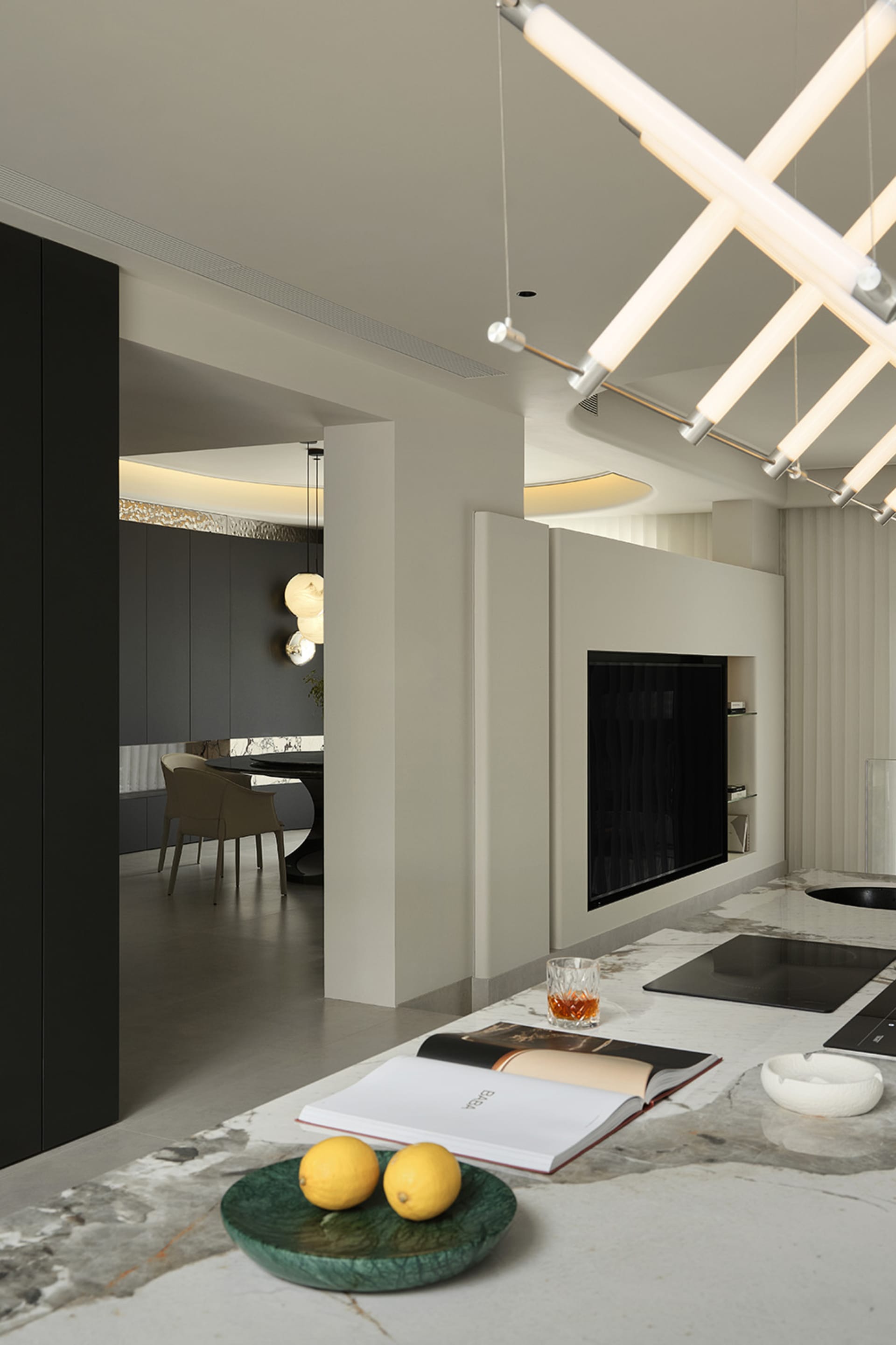 Modern kitchen with marble countertops, a built-in fireplace, and contemporary lighting fixtures.