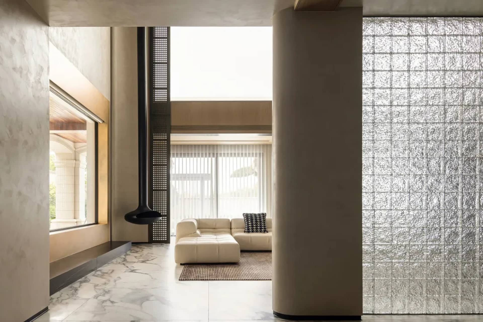 Modern minimalist living room featuring marble, concrete, and glass materials.