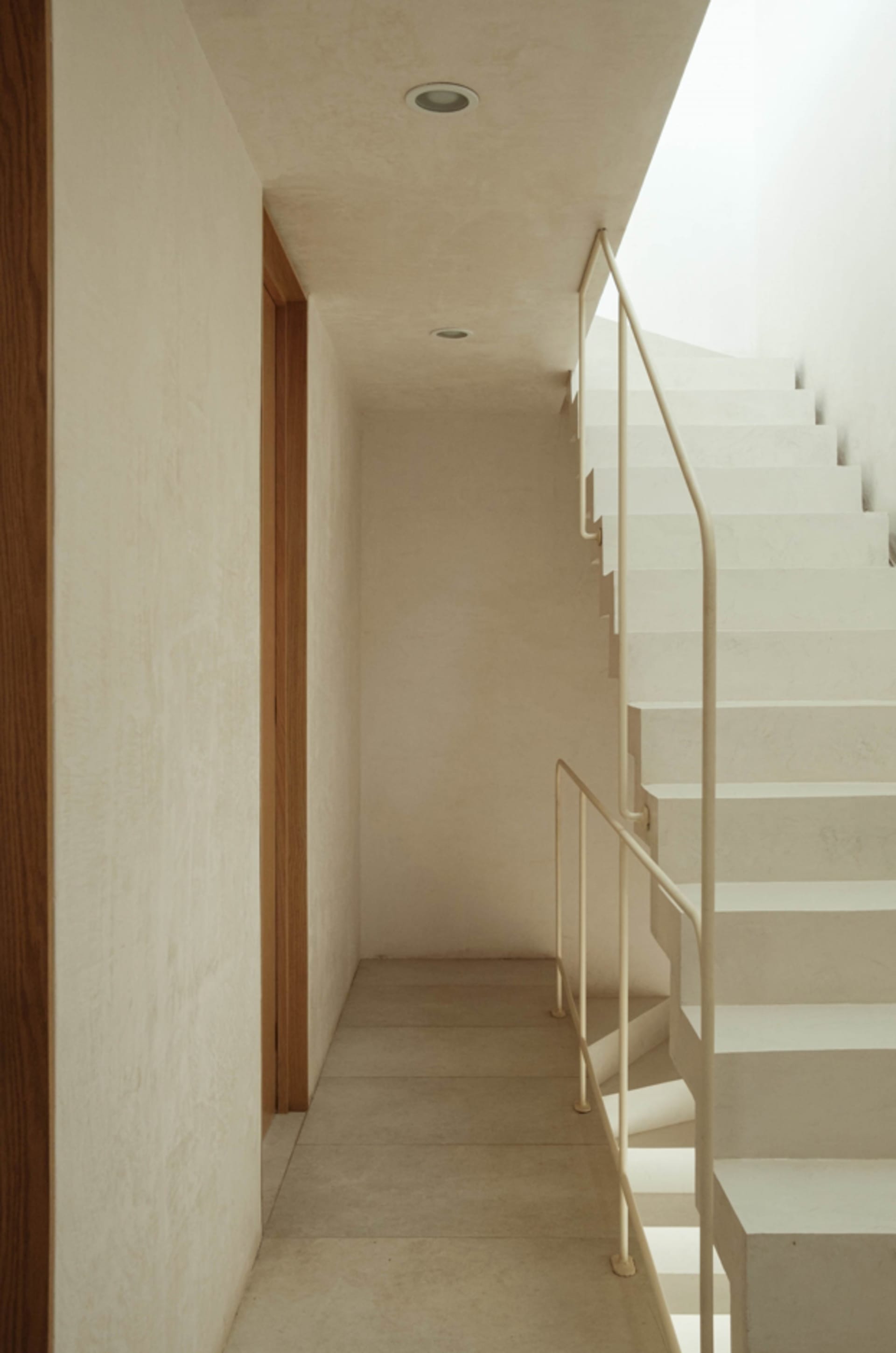 Modern minimalist concrete staircase with metal railings, viewed from a side angle.