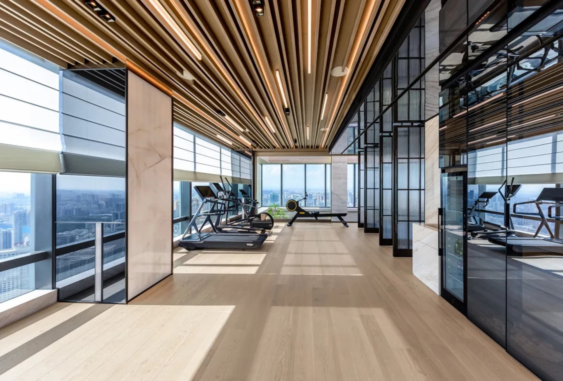 Modern gym room with wooden floors, steel accents, glass walls, and concrete elements.