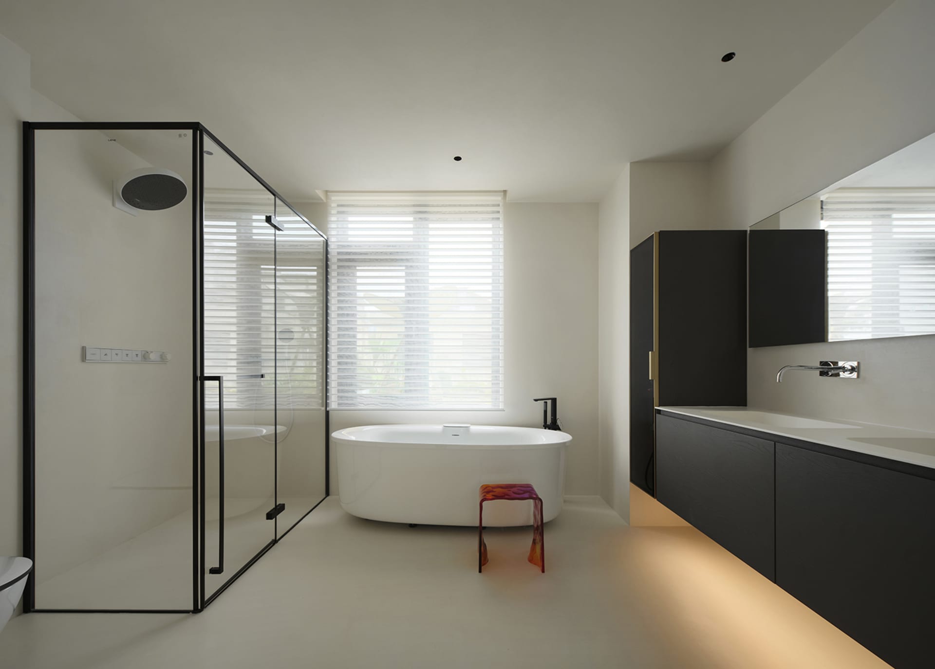 A modern residential bathroom featuring a glass shower enclosure, a freestanding bathtub, and sleek black cabinetry with unde