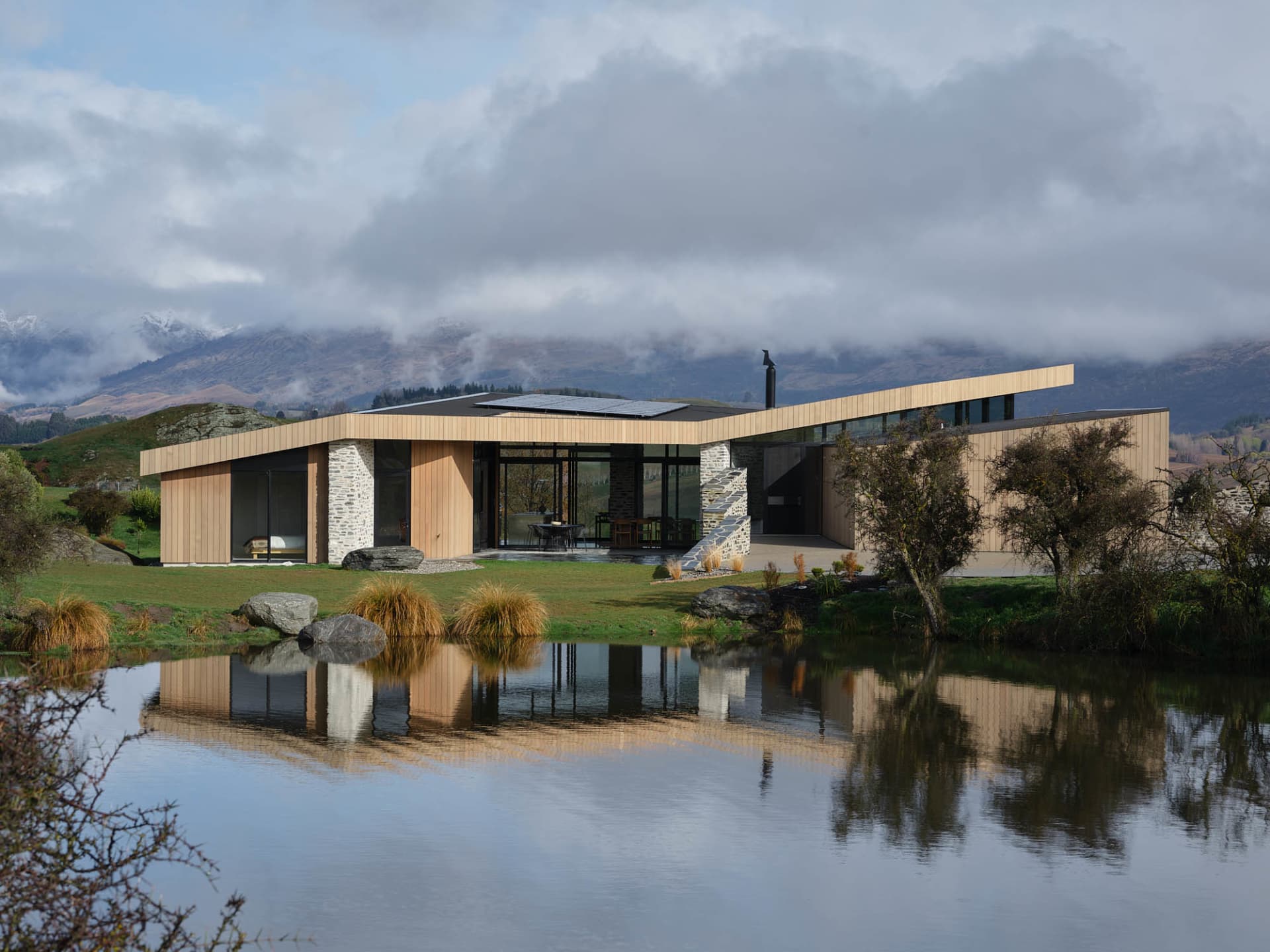 A modern house with a wooden exterior situated in a rural area.