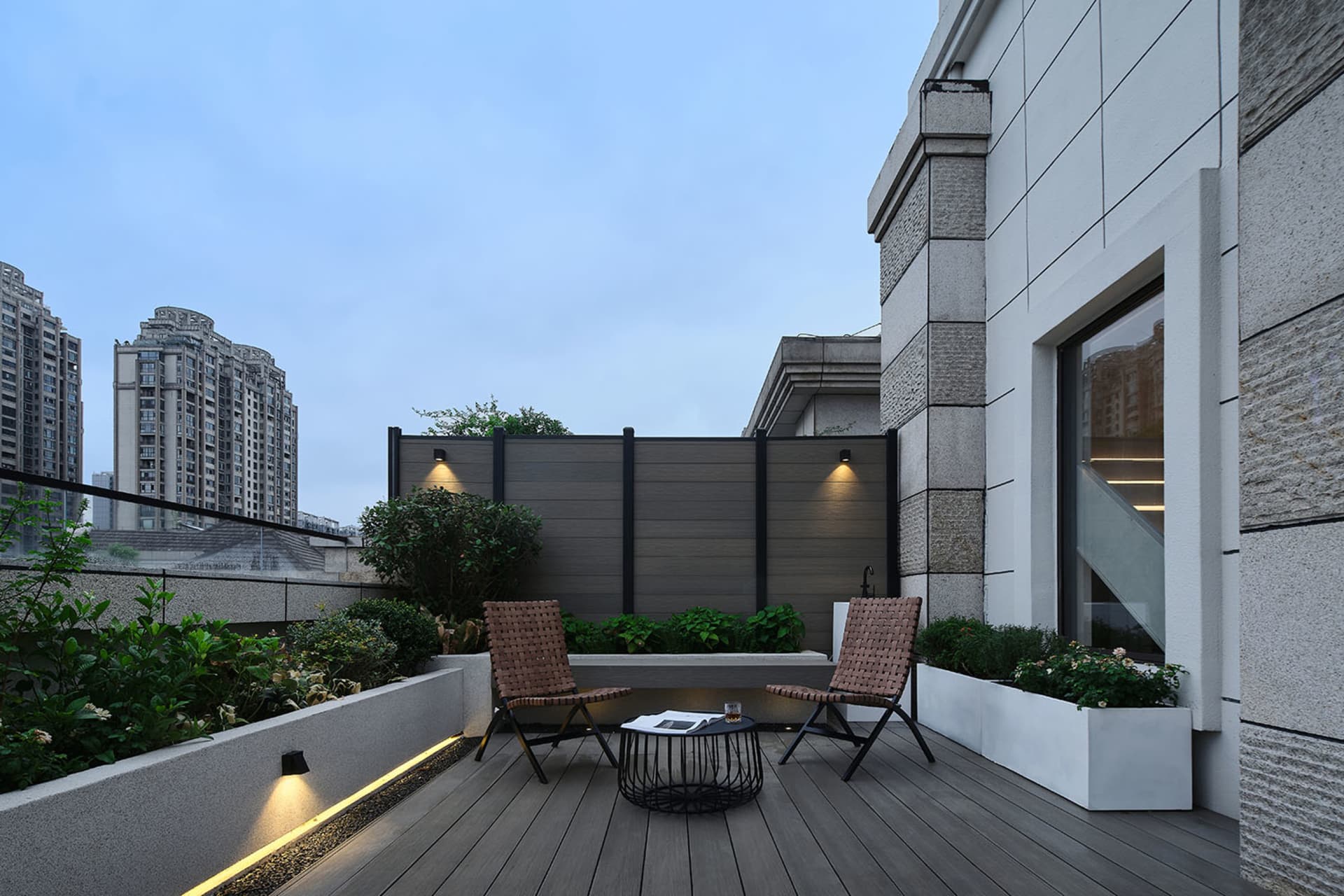 A contemporary roof deck featuring timber laminate flooring, outdoor furniture, and landscaping.