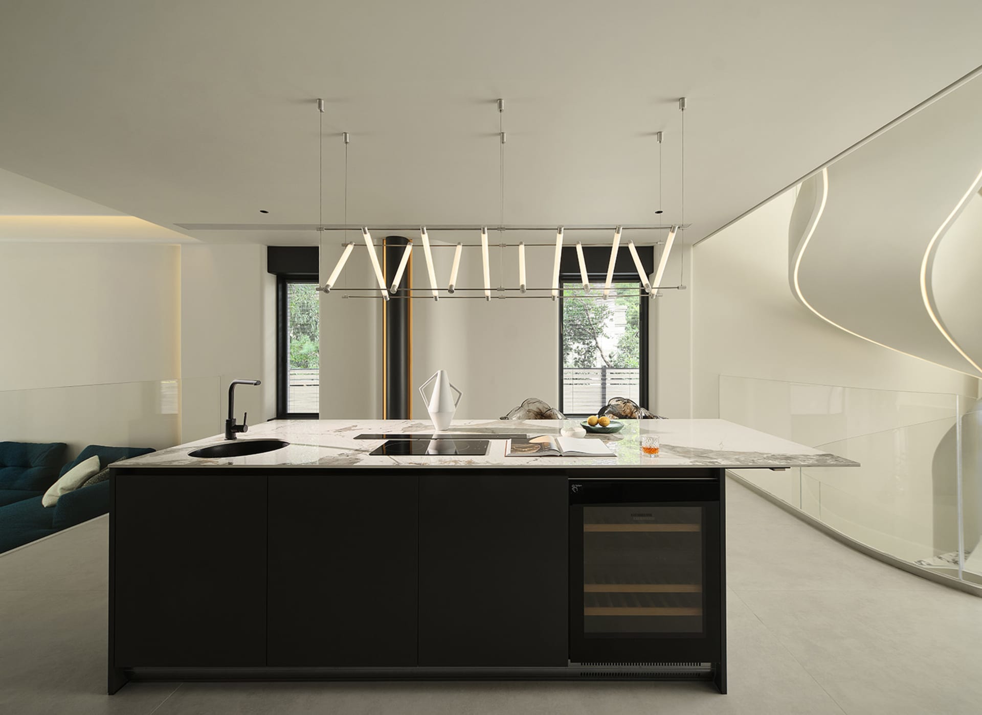 A modern kitchen featuring a large island with a marble countertop and black cabinets.