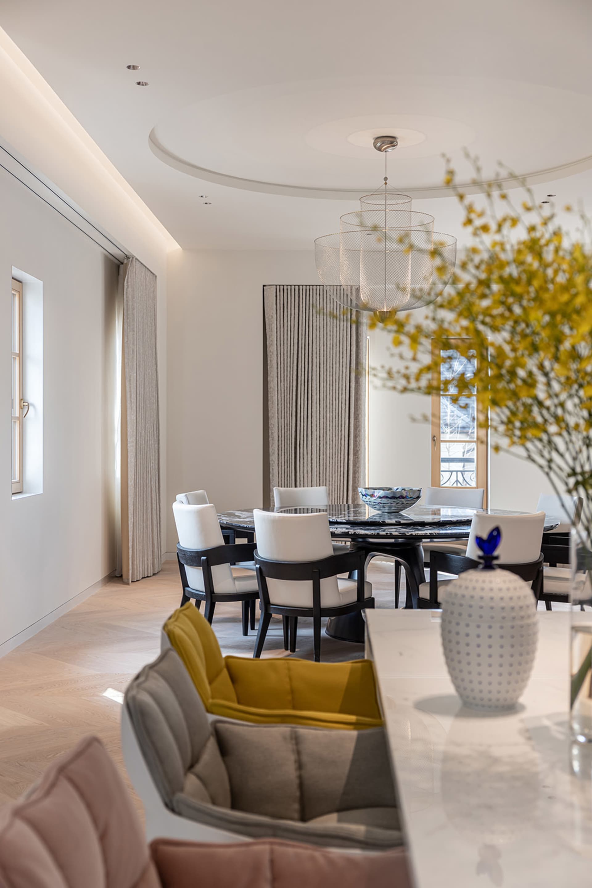 Modern dining room with marble table and chairs, featuring elegant chandeliers